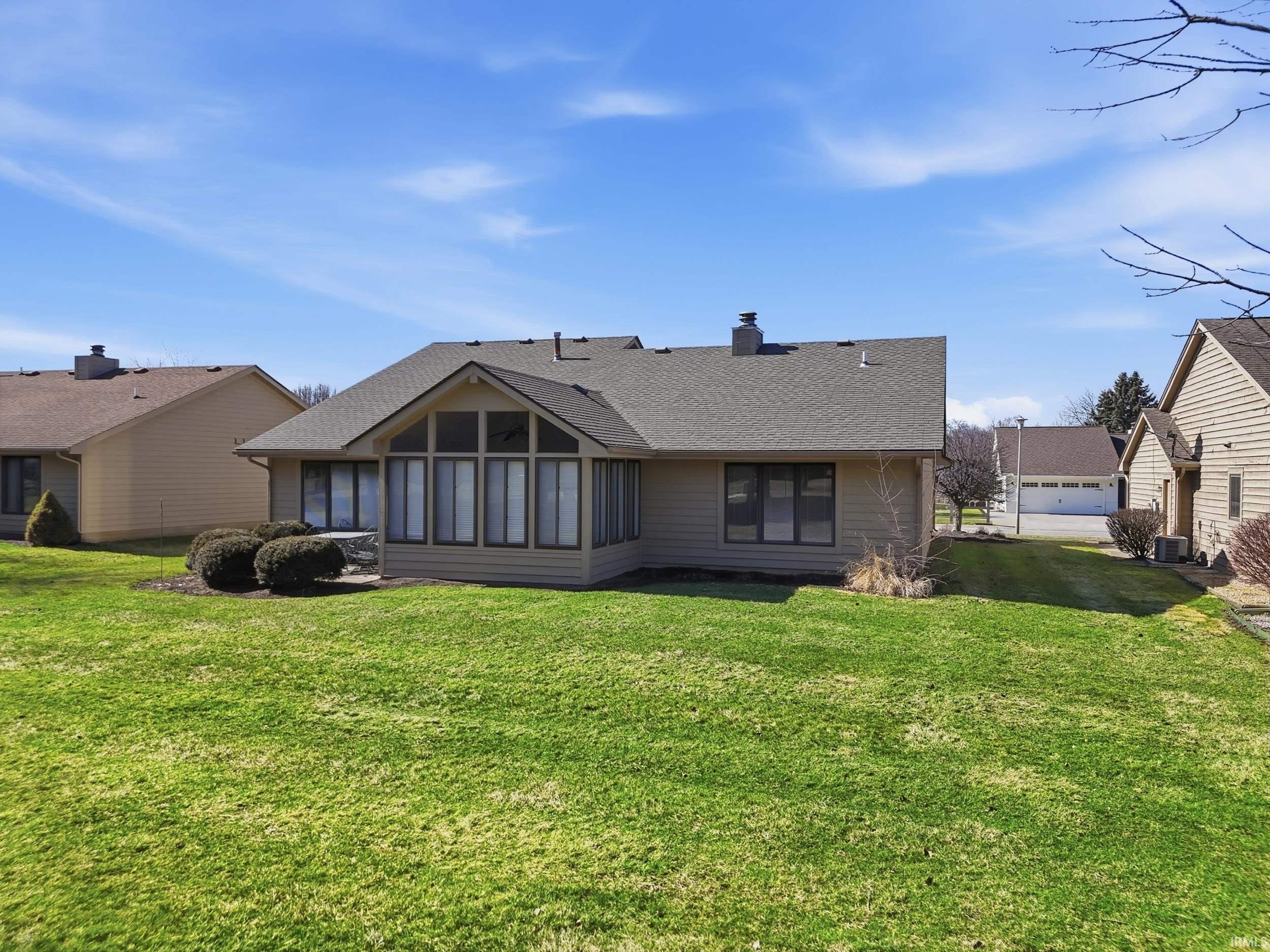 Rear view of property with a sunroom, a shingled roof, a lawn, and a chimney