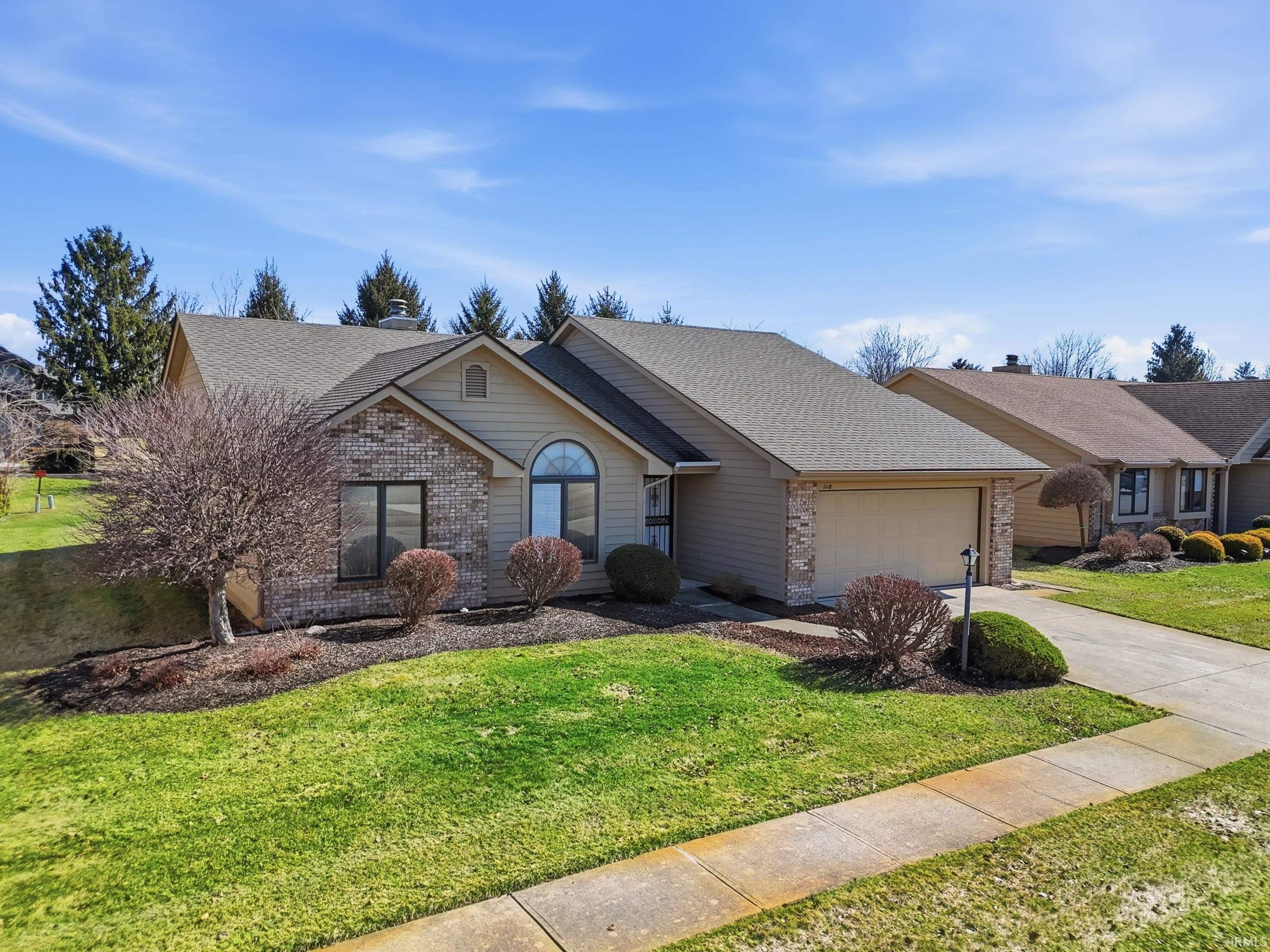 Ranch-style house with brick siding, roof with shingles, a front lawn, and driveway