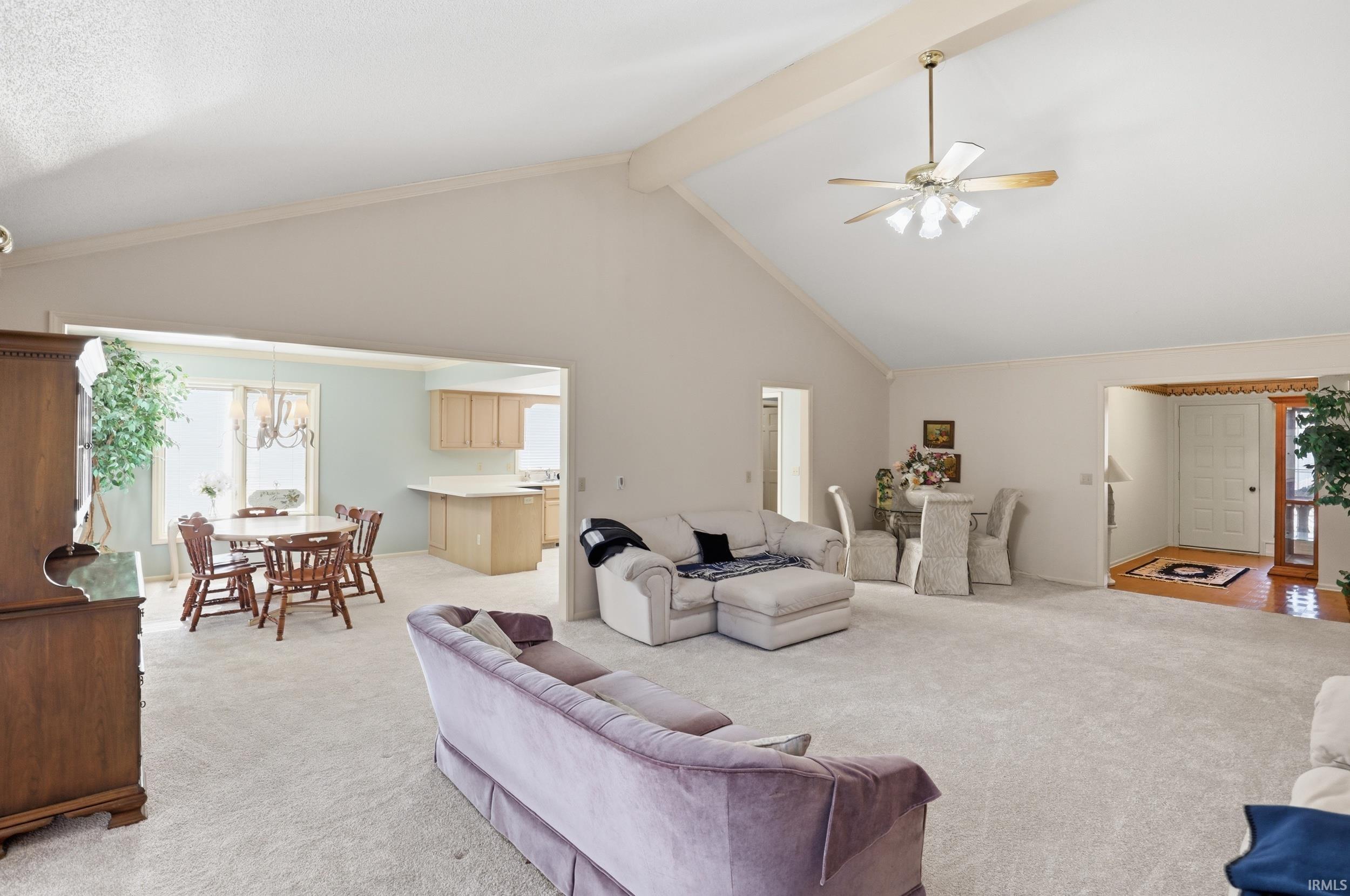 Living area featuring light colored carpet, a ceiling fan, and a chandelier