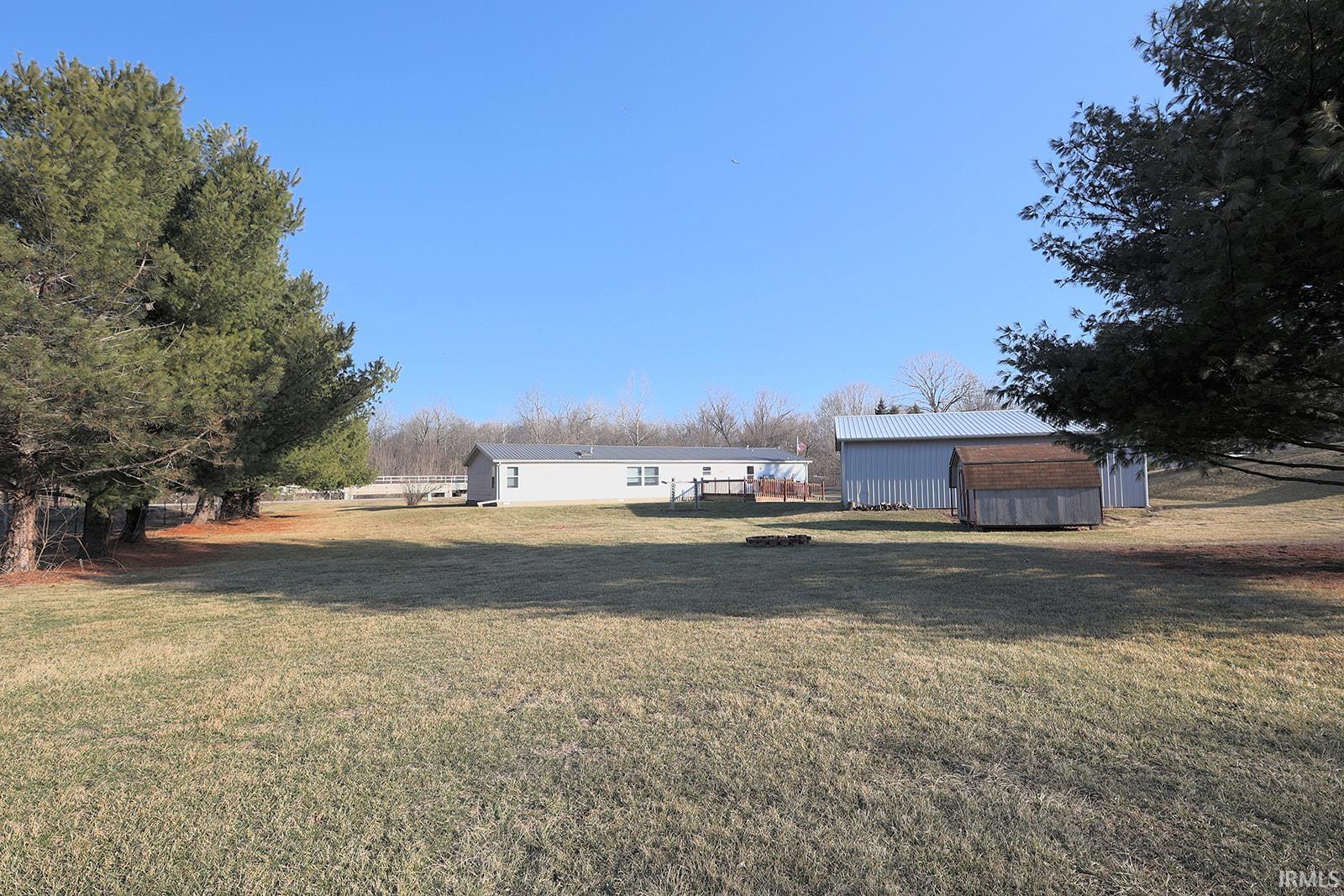 View of green lawn with an outdoor structure and an outdoor fire pit