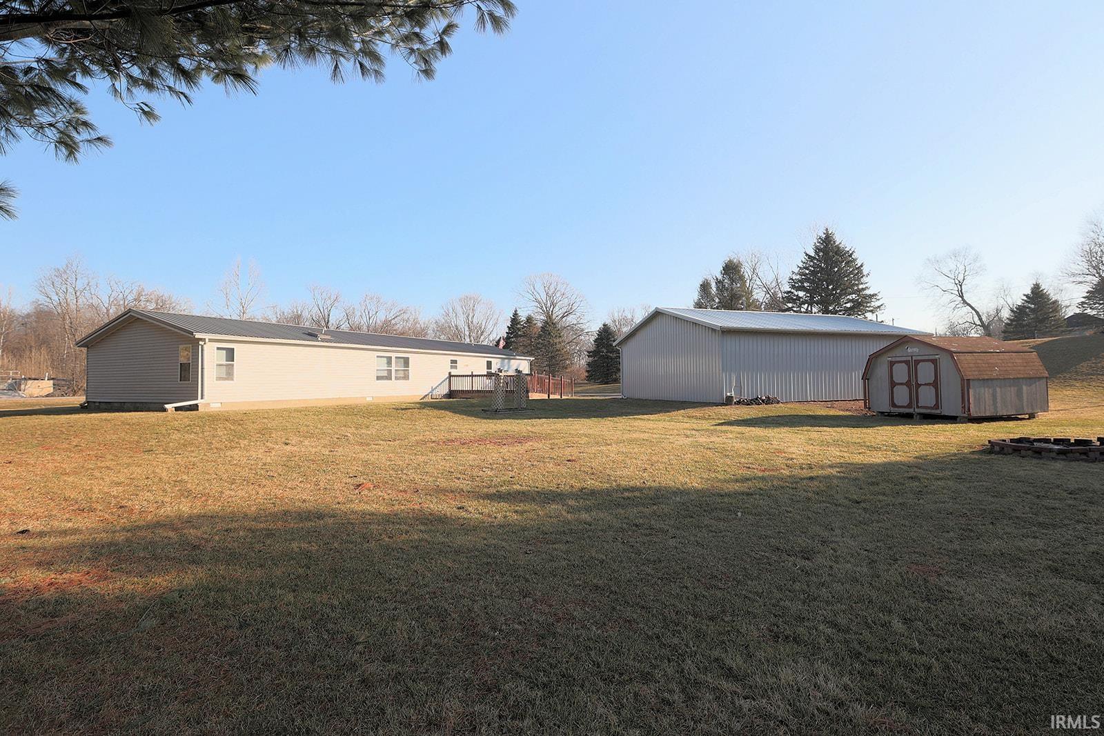 View of green lawn featuring a storage unit and a wooden deck