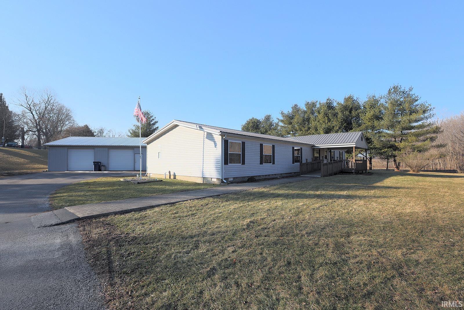 Manufactured / mobile home featuring a front yard, a metal roof, and driveway
