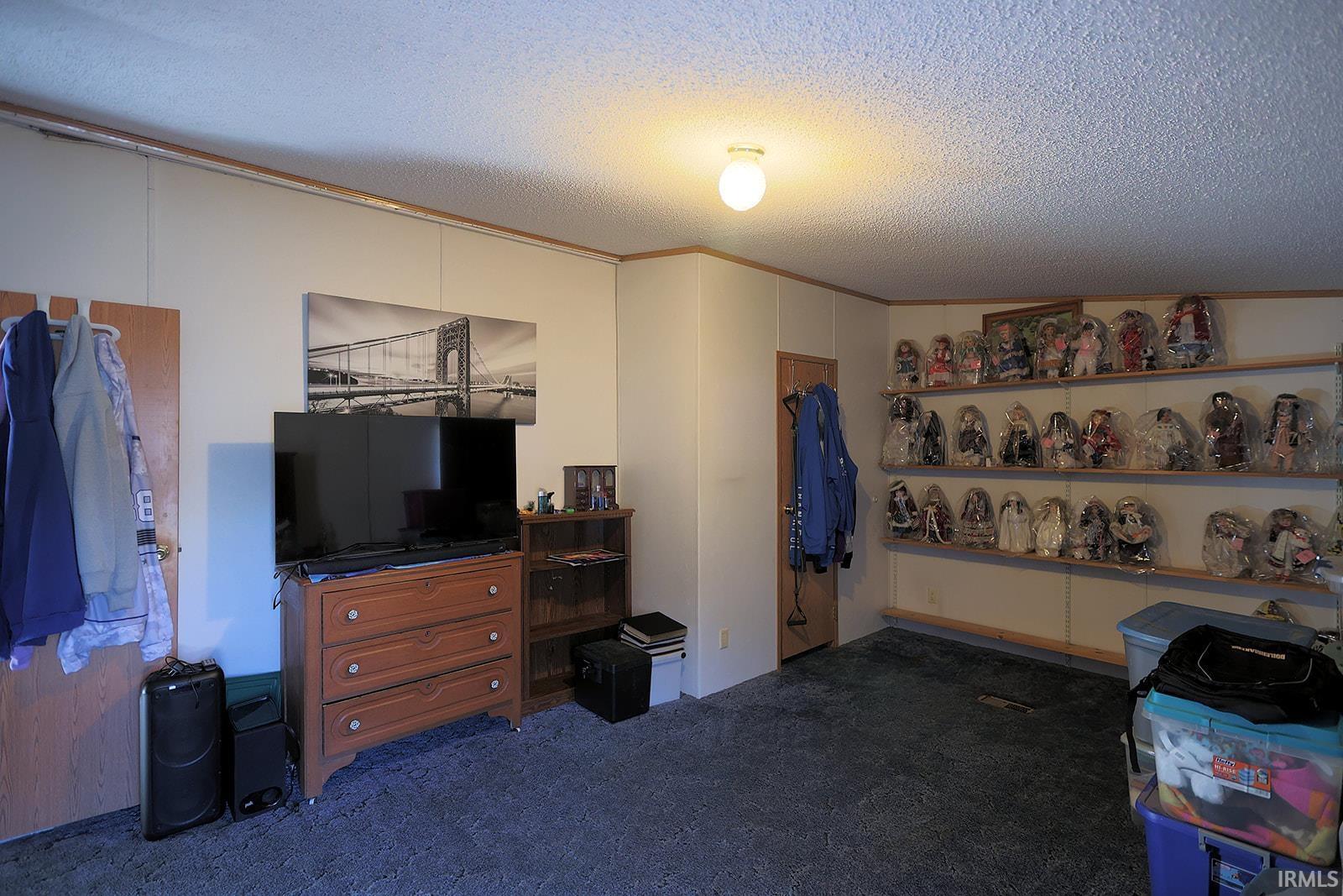 Bedroom featuring a textured ceiling, dark carpet, and crown molding