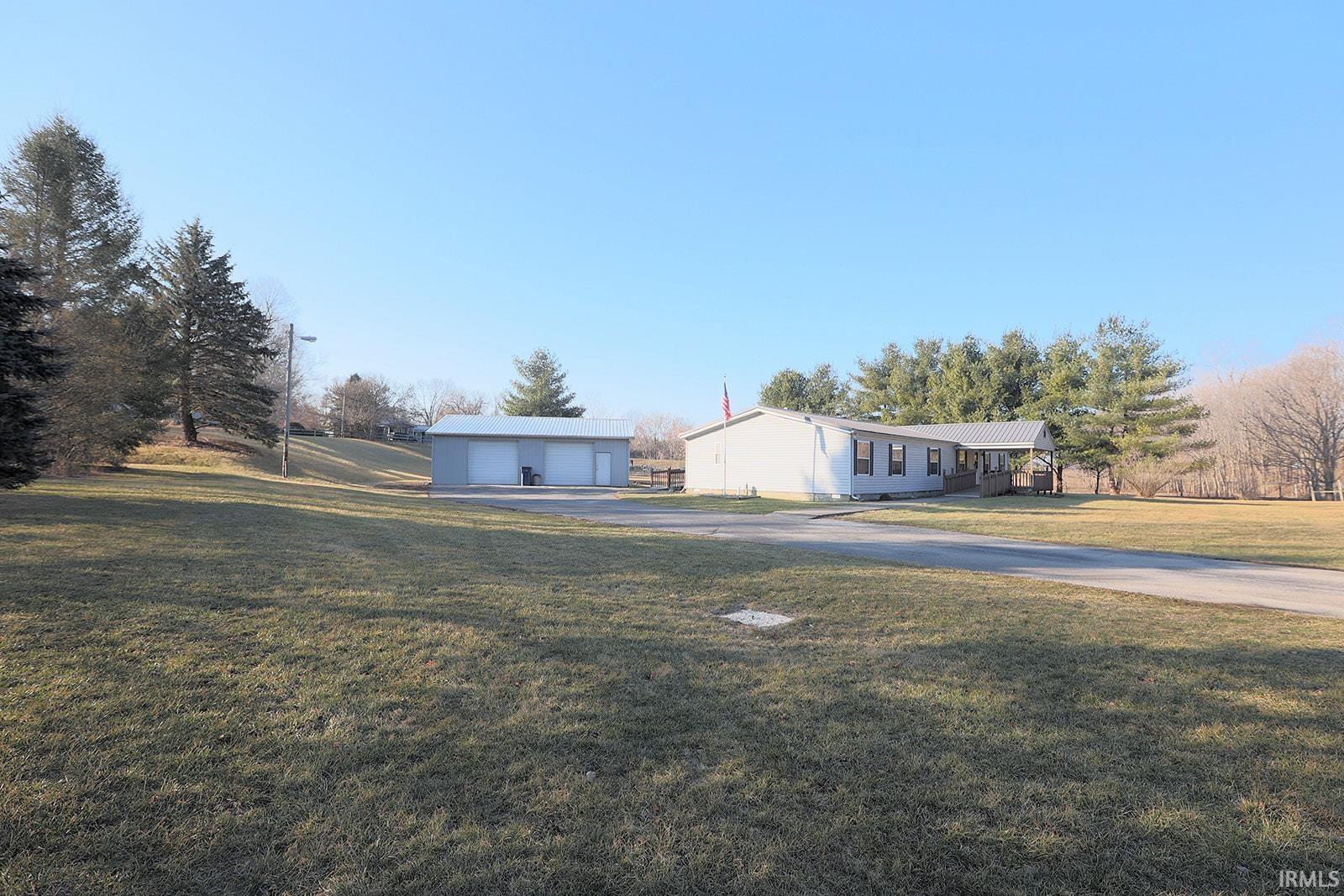 View of front facade featuring a front lawn, a garage, and an outbuilding