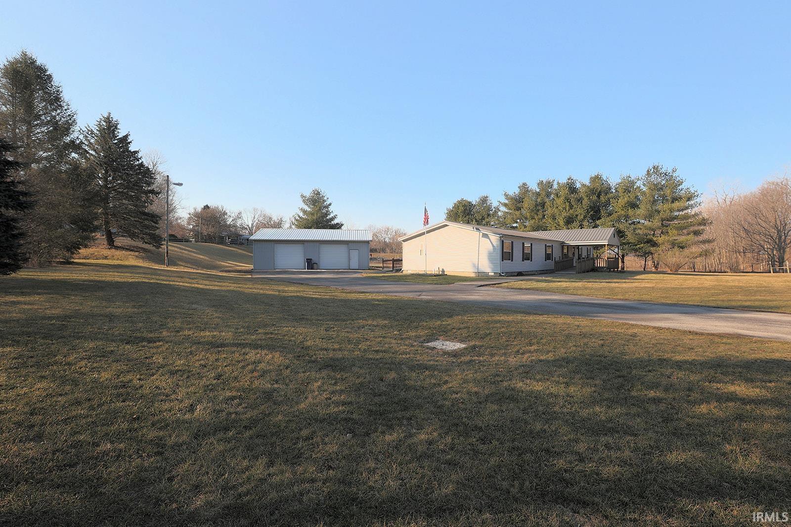 View of grassy yard with a detached garage and an outbuilding