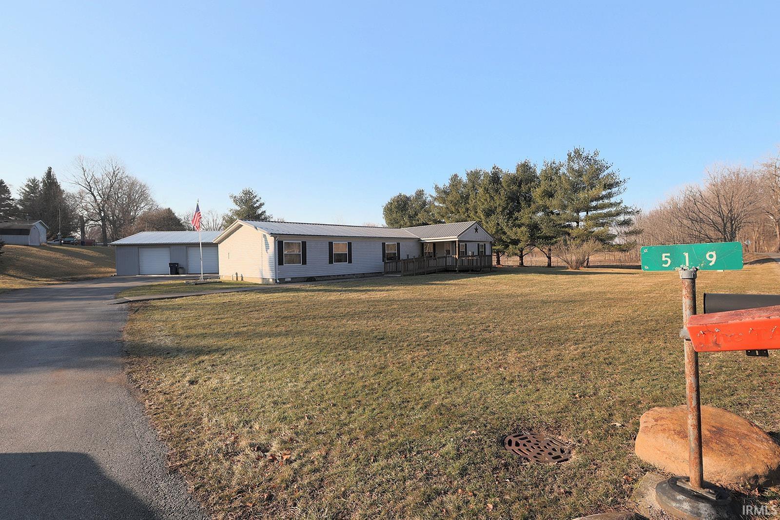 Ranch-style home with a front yard, a detached garage, and an outdoor structure