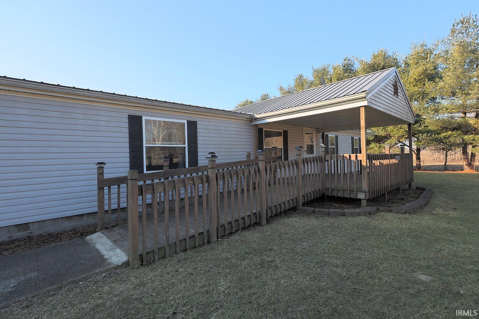 Back of house featuring a deck, a metal roof, and a lawn