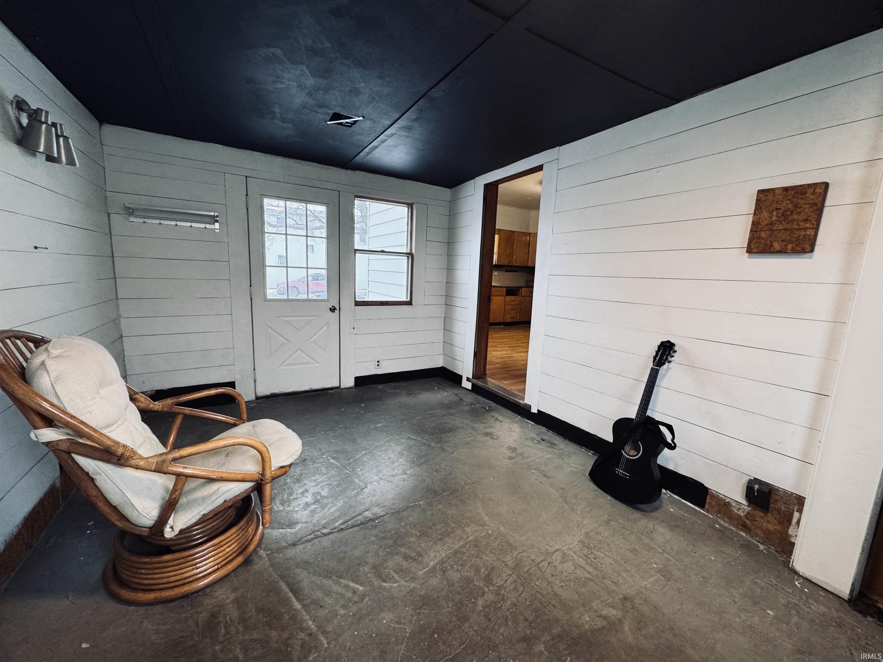 Unfurnished room featuring wood walls and concrete flooring