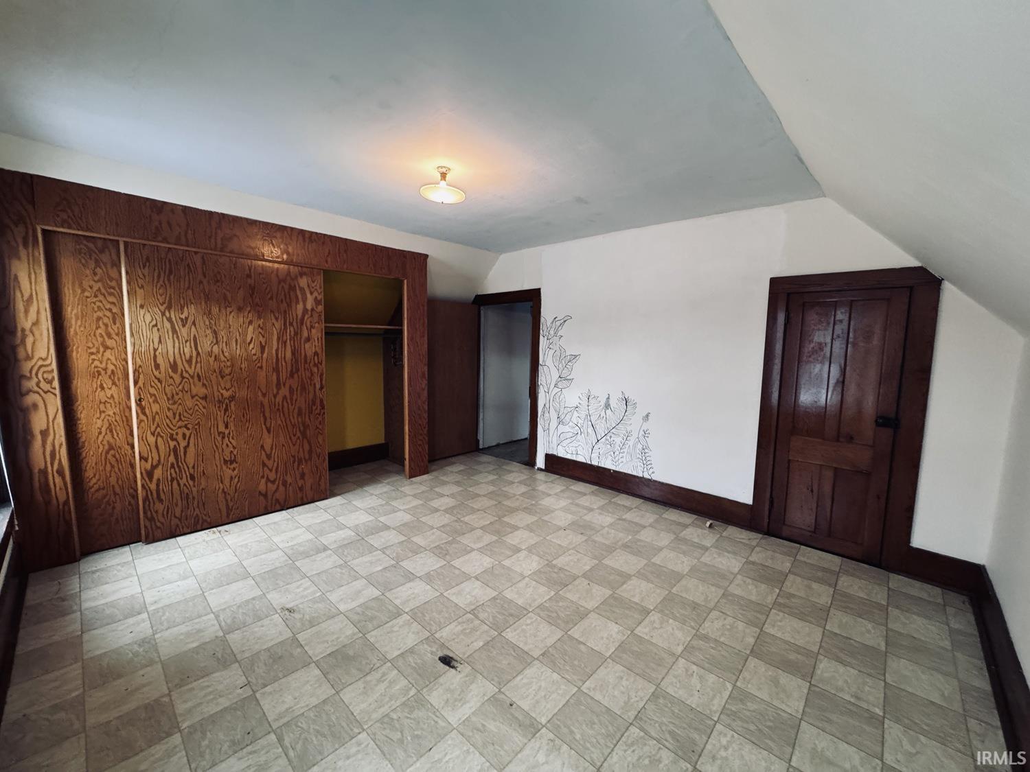 Unfurnished bedroom with a closet and vaulted ceiling
