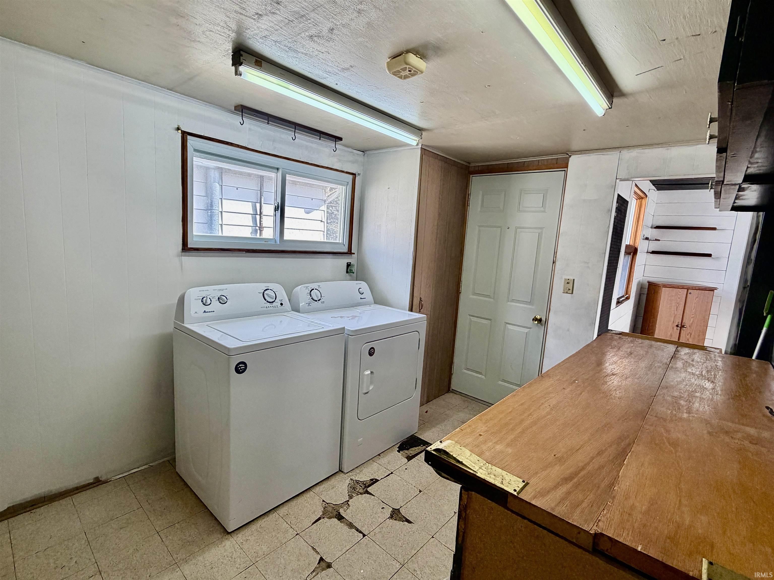 Laundry area with light flooring, washer and dryer, and a textured ceiling