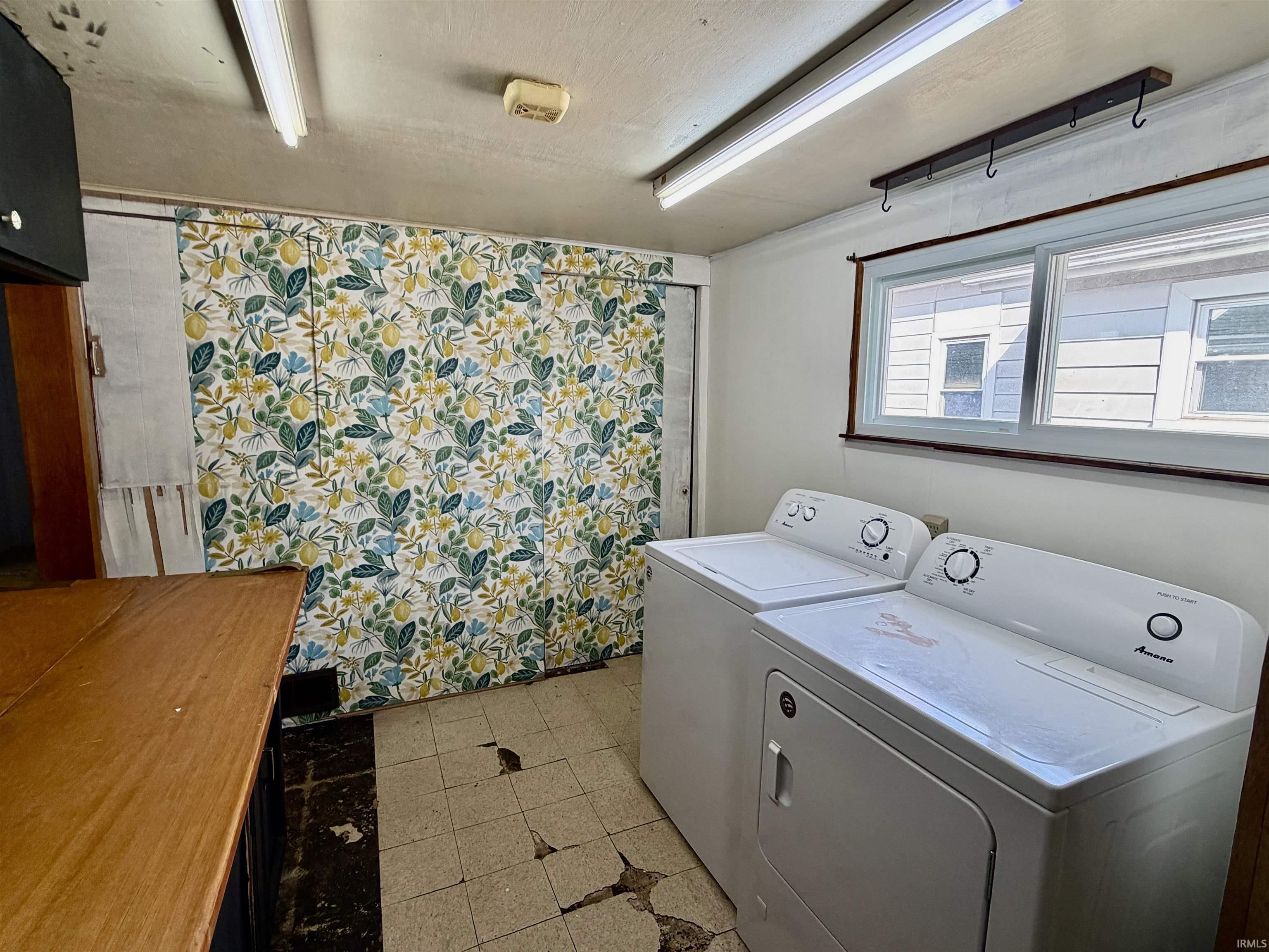 Laundry room with separate washer and dryer and light tile patterned floors