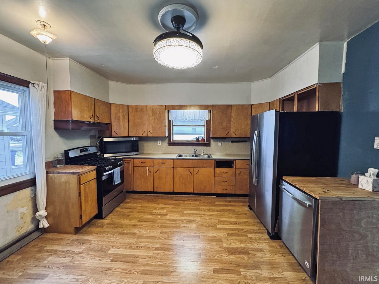 Kitchen with stainless steel appliances, wood finish cabinets, and light wood-style floors. Can be an eat-in kitchen.