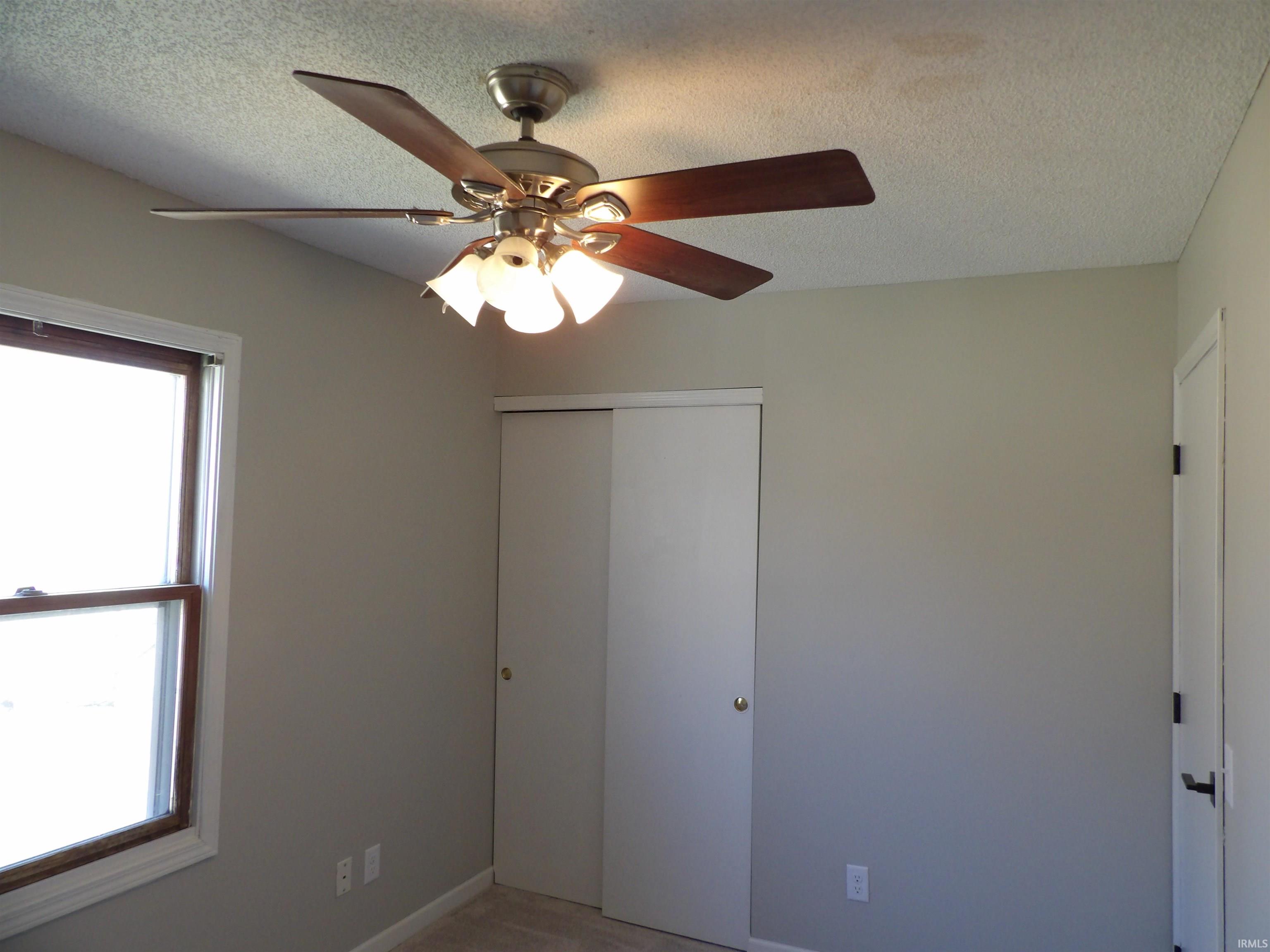 Unfurnished bedroom with ceiling fan, a textured ceiling, and a closet