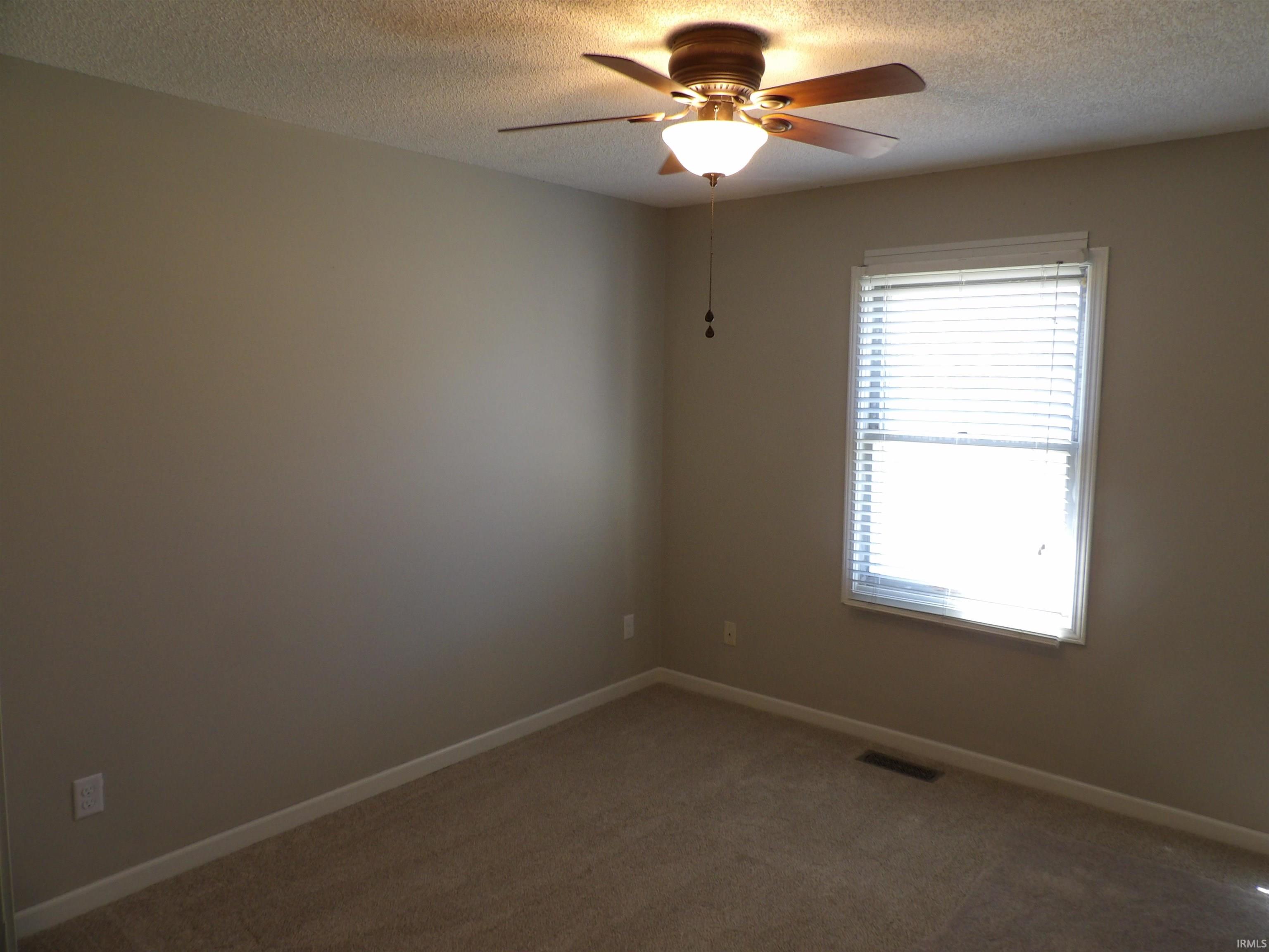 Spare room featuring ceiling fan, carpet flooring, and a textured ceiling