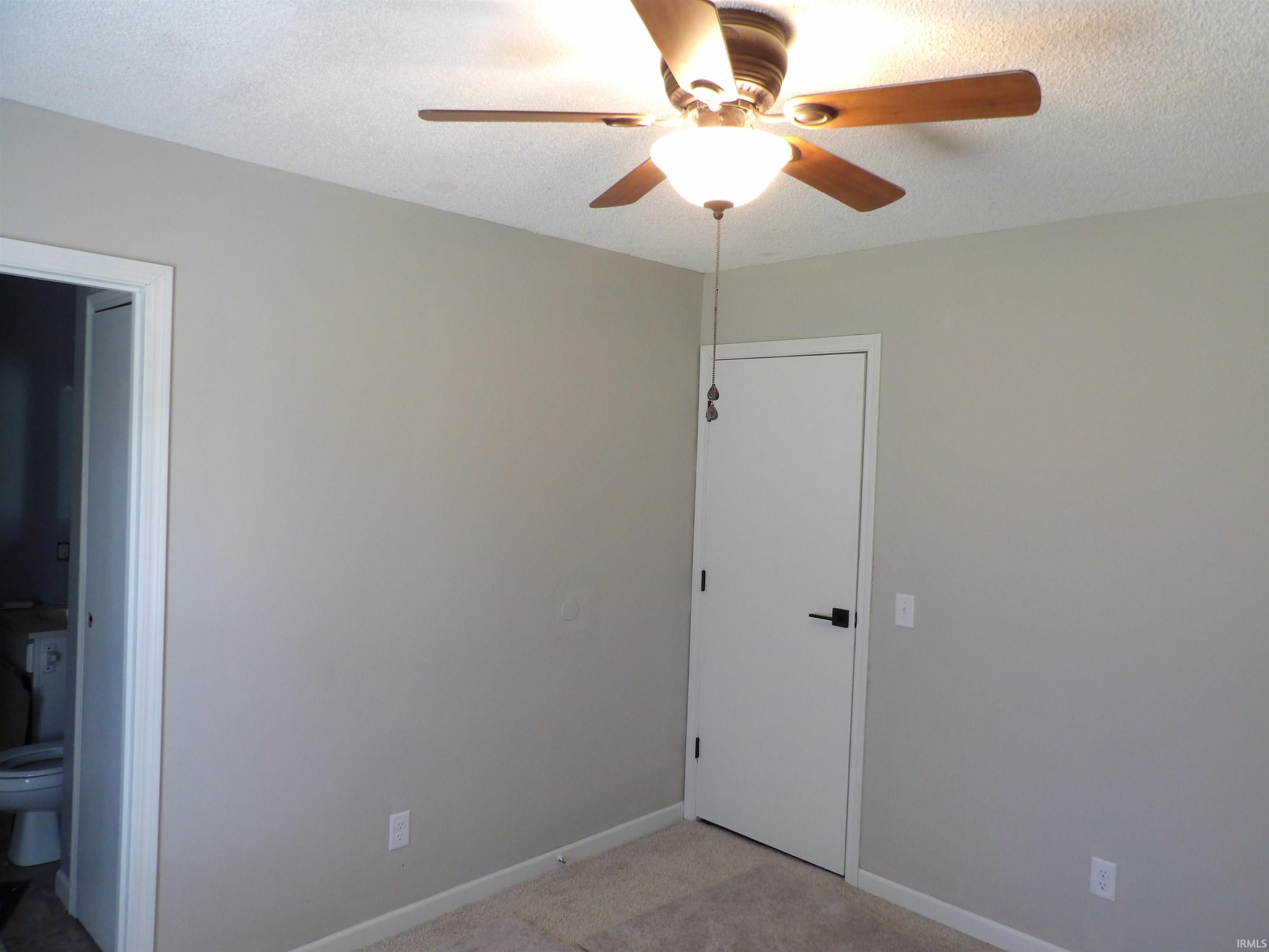 Spare room featuring a ceiling fan, light carpet, and a textured ceiling