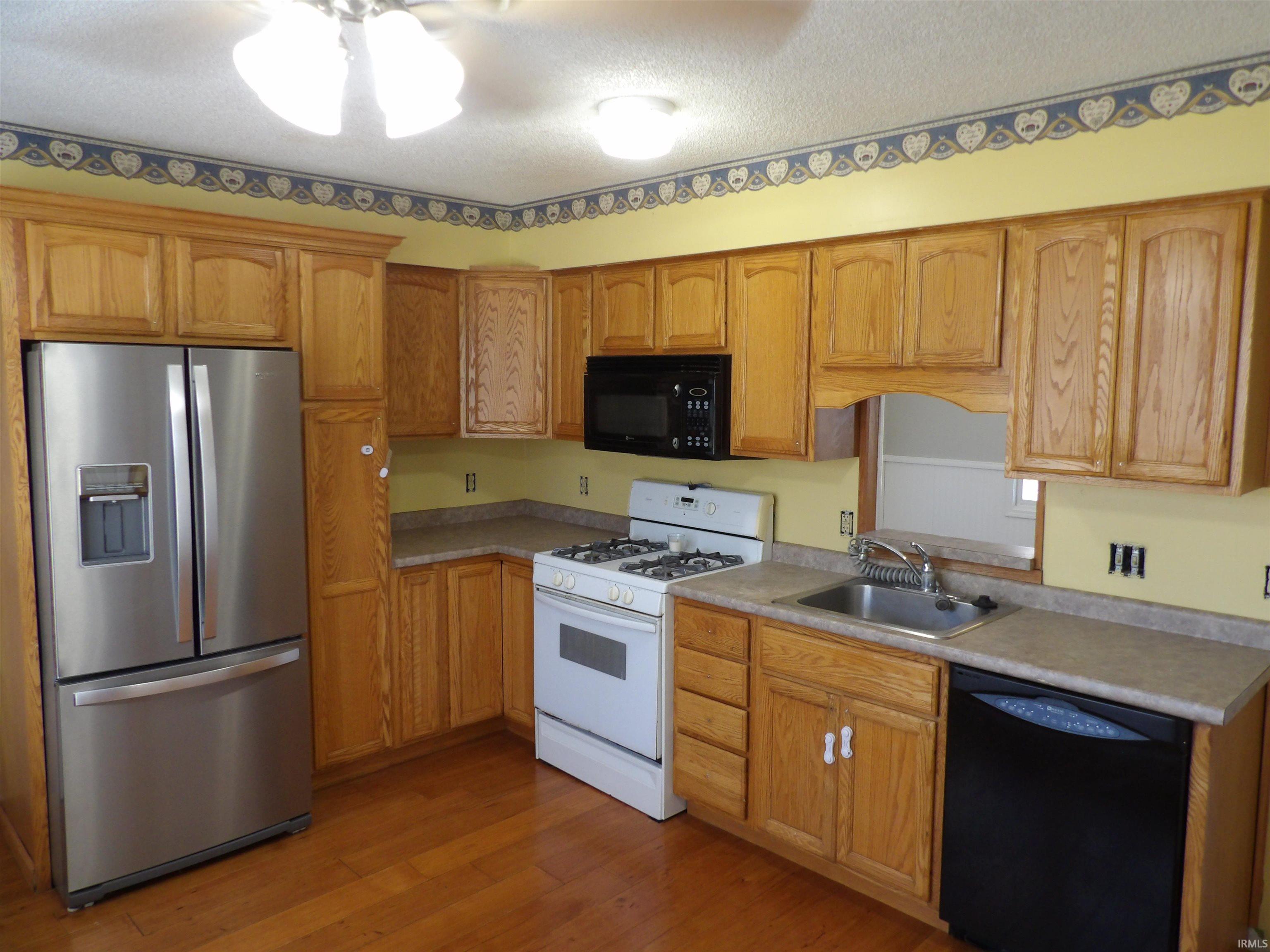 Kitchen featuring black appliances, dark wood-style floors, a textured ceiling, and light countertops