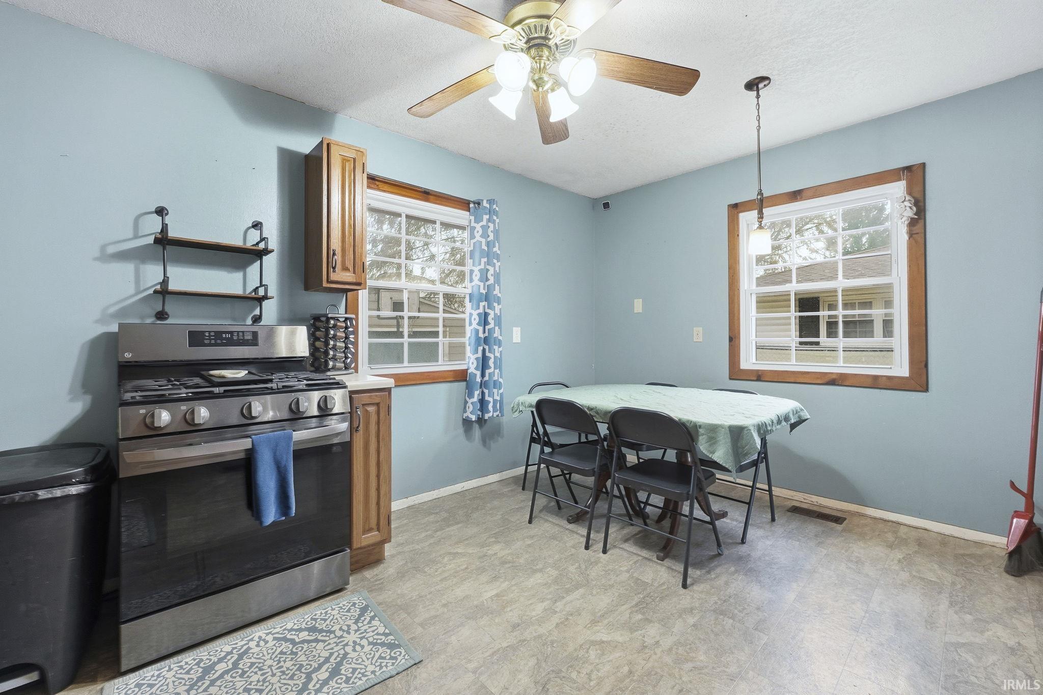Kitchen featuring stainless steel gas range oven, a ceiling fan, a textured ceiling, light floors, and light countertops