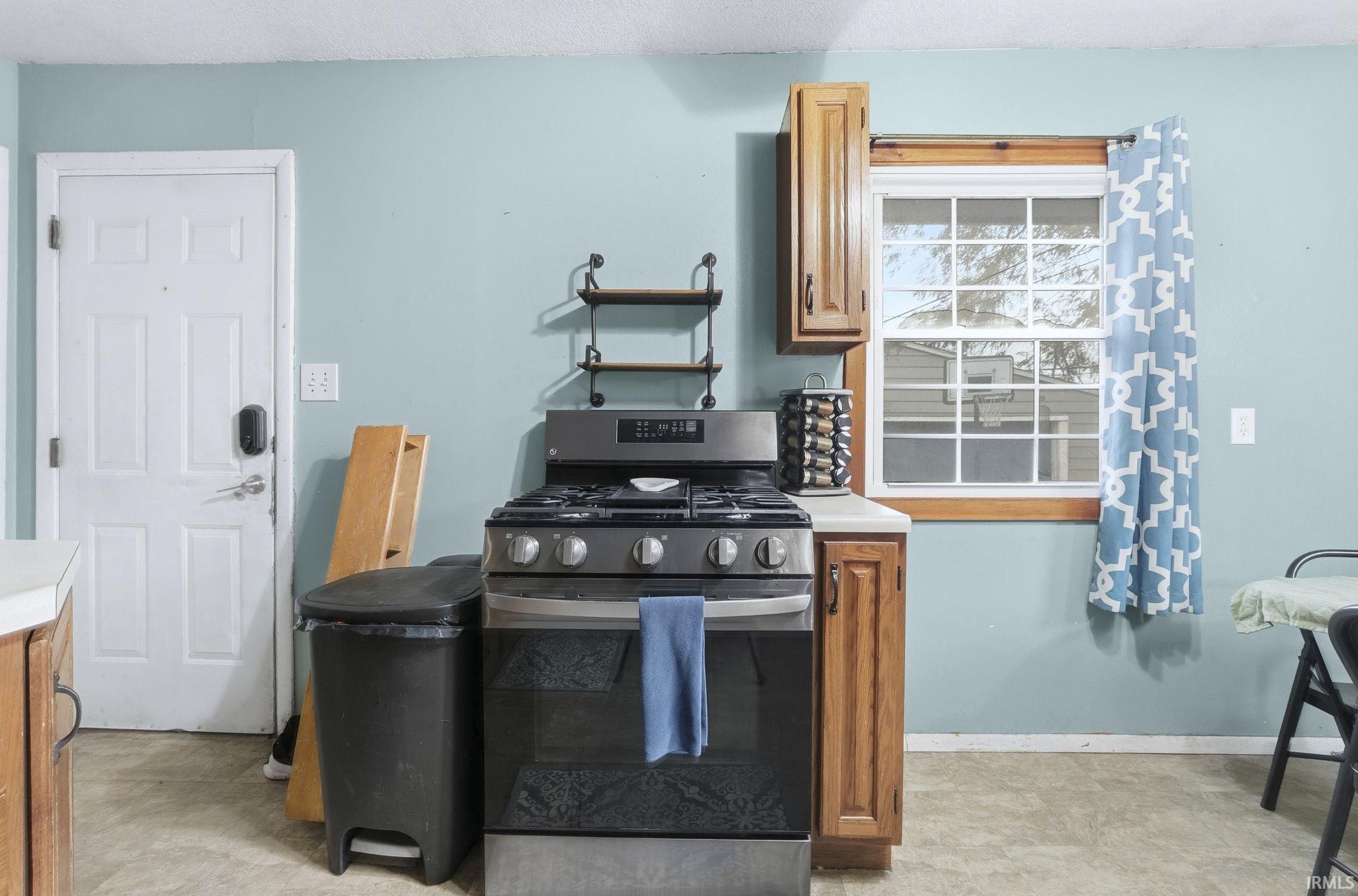 Kitchen featuring stainless steel range with gas stovetop, light countertops, and brown cabinets