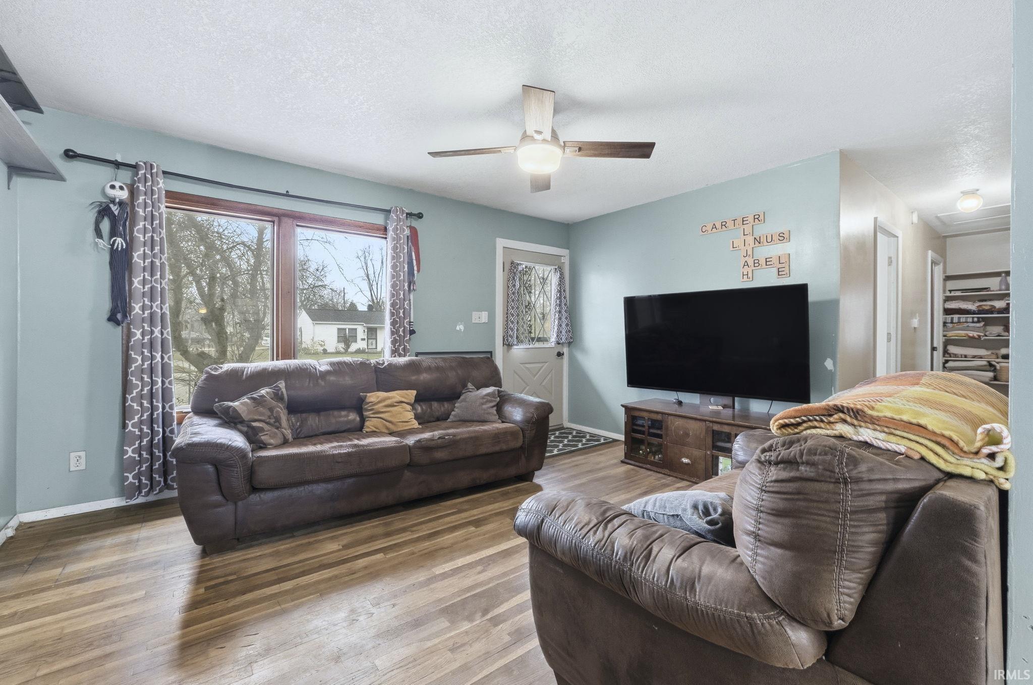 Living area featuring wood finished floors, a textured ceiling, and ceiling fan