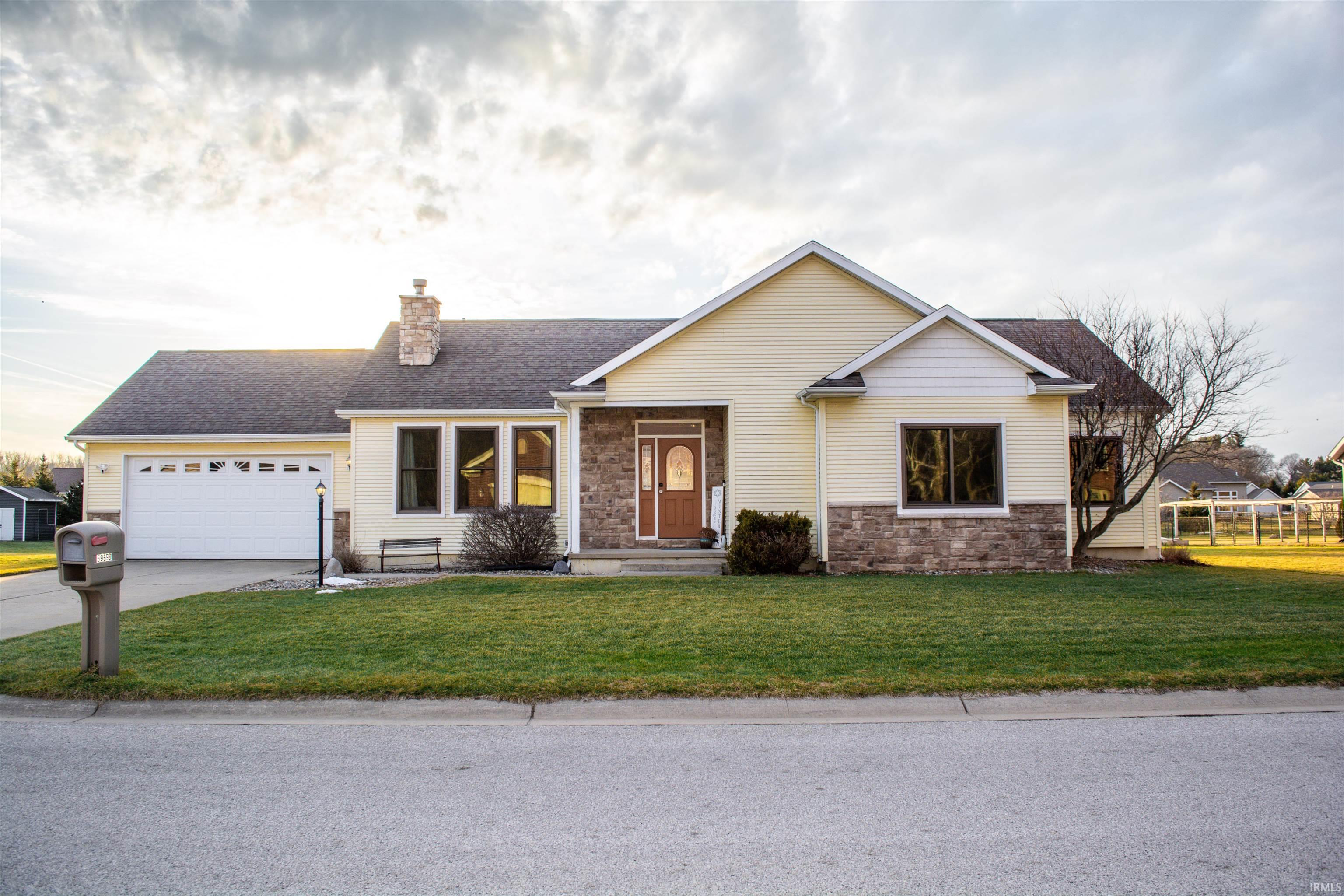View of front of house featuring a front yard, a chimney, a garage, stone siding, and a shingled roof
