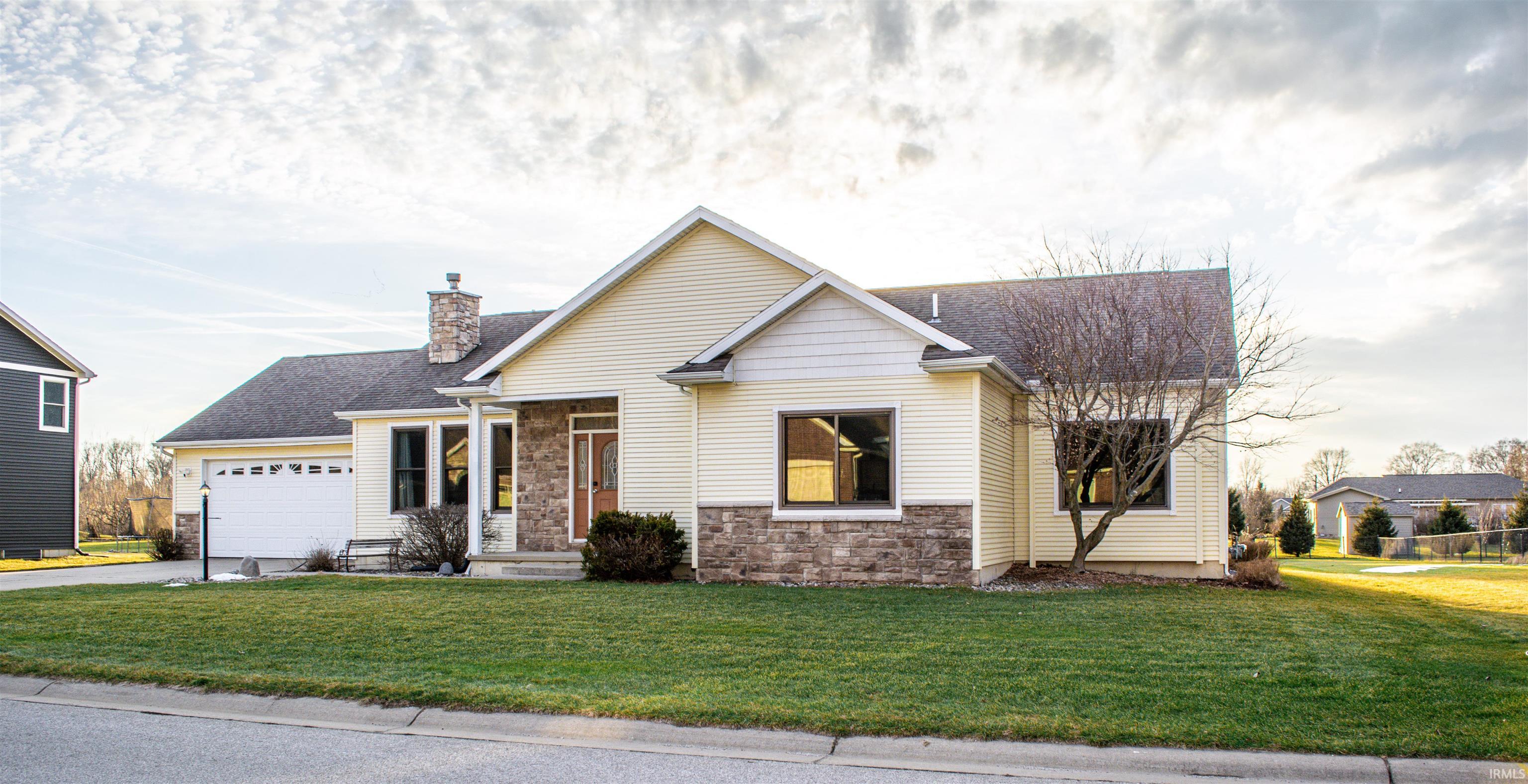 View of front of house featuring a front lawn, stone siding, a garage, and a chimney