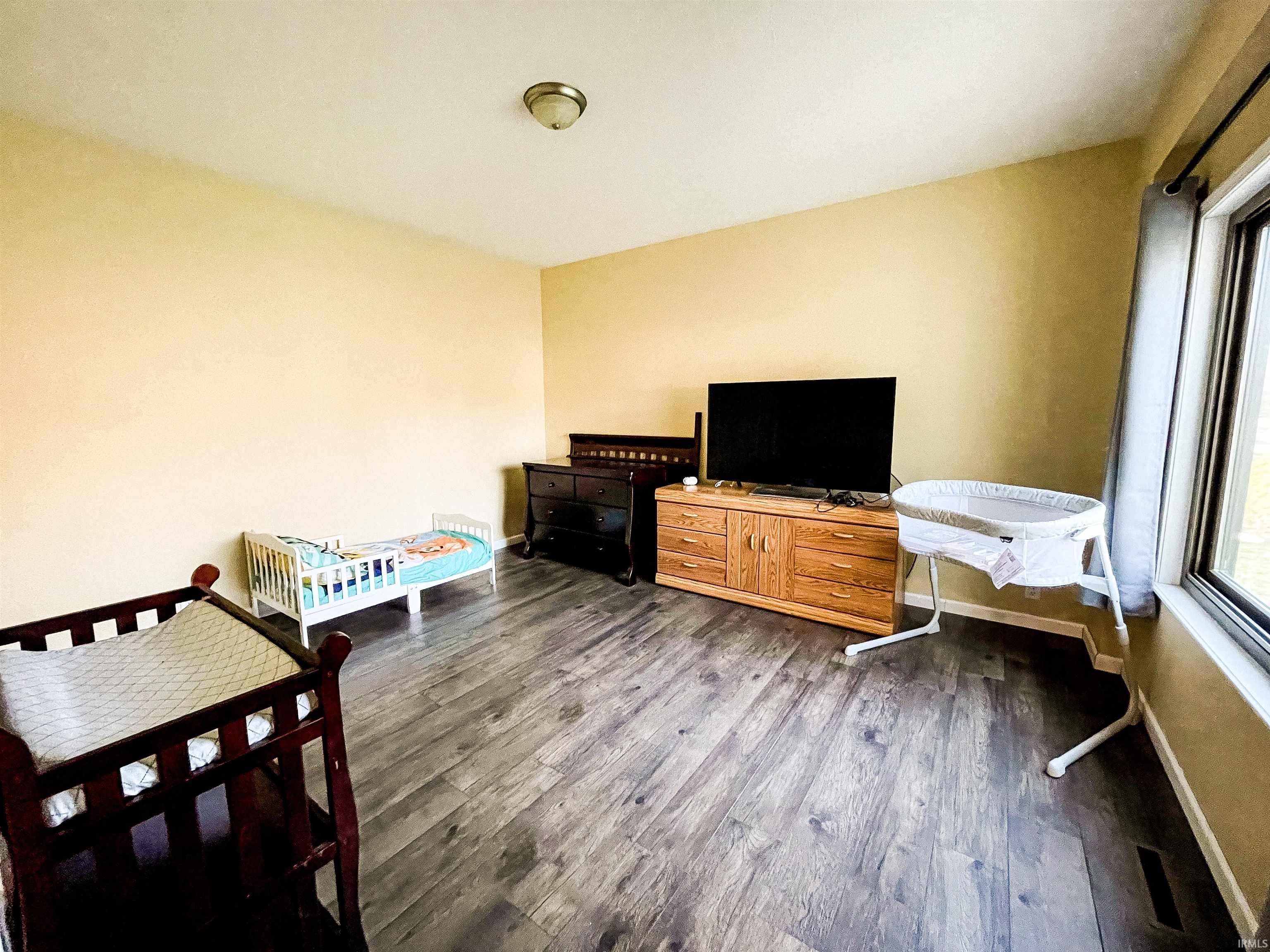 Bedroom with dark wood-style flooring and baseboards