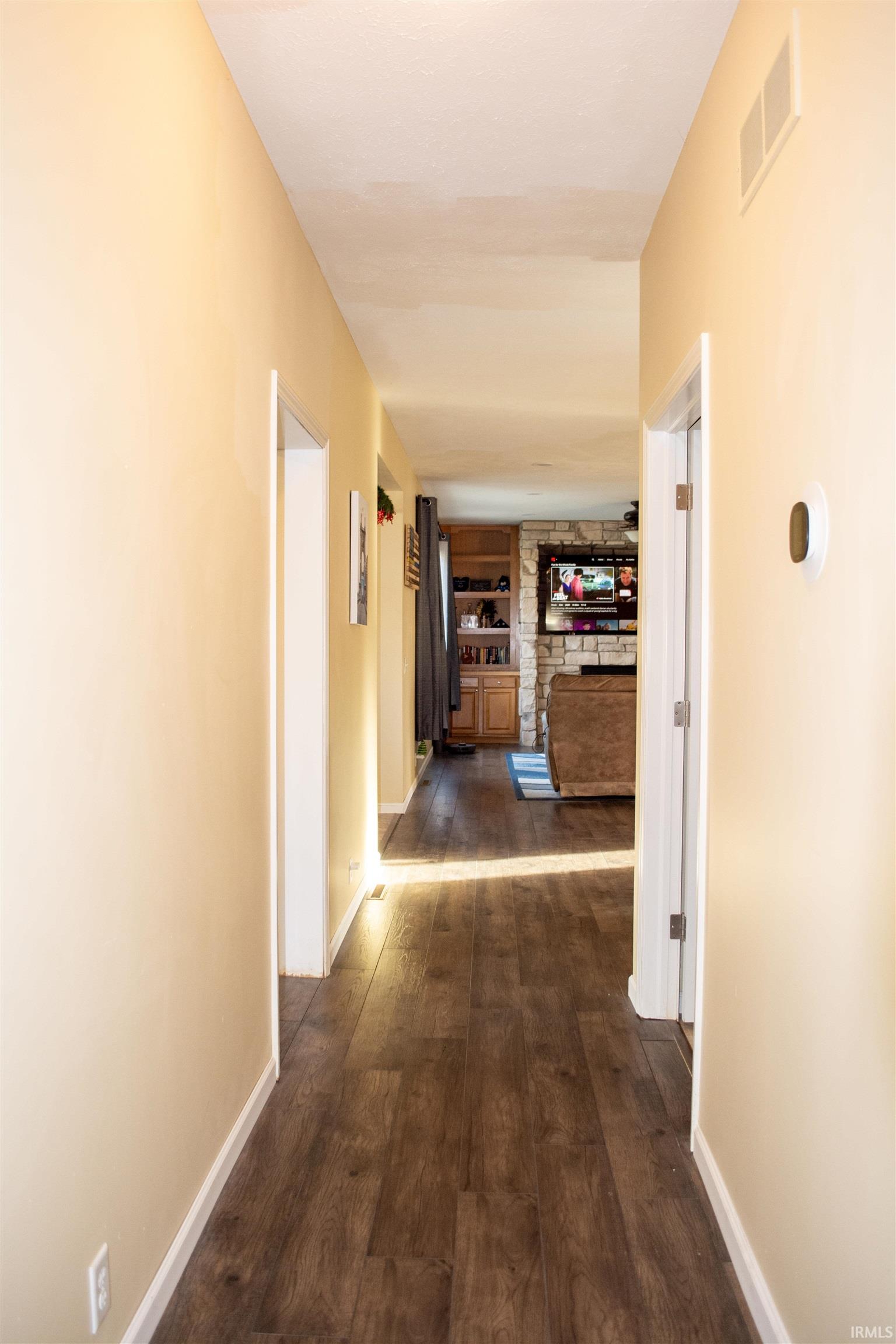 Corridor with dark wood-style flooring and built in shelves