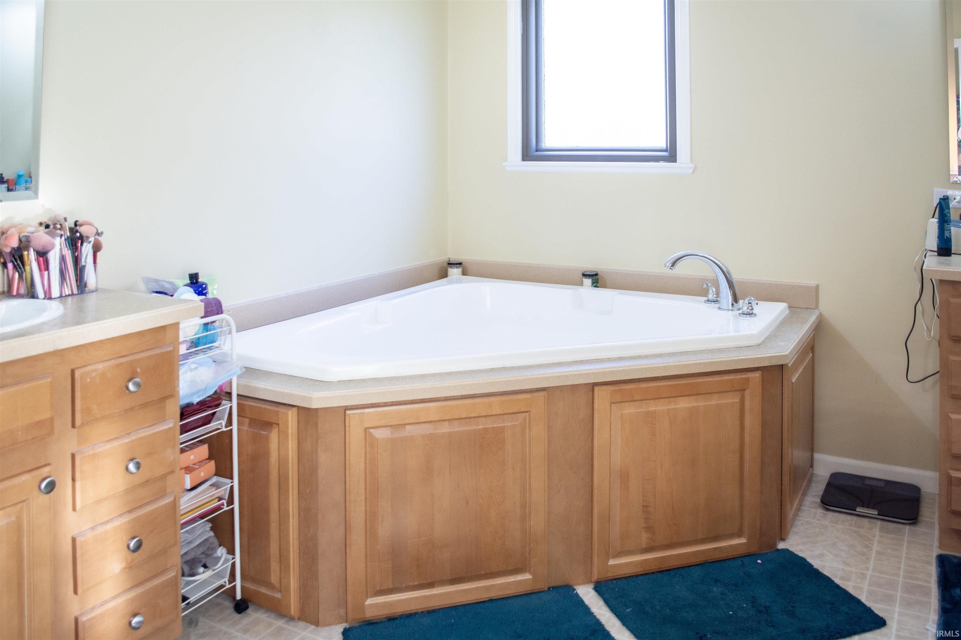Bathroom featuring vanity, a bath, and light tile patterned flooring