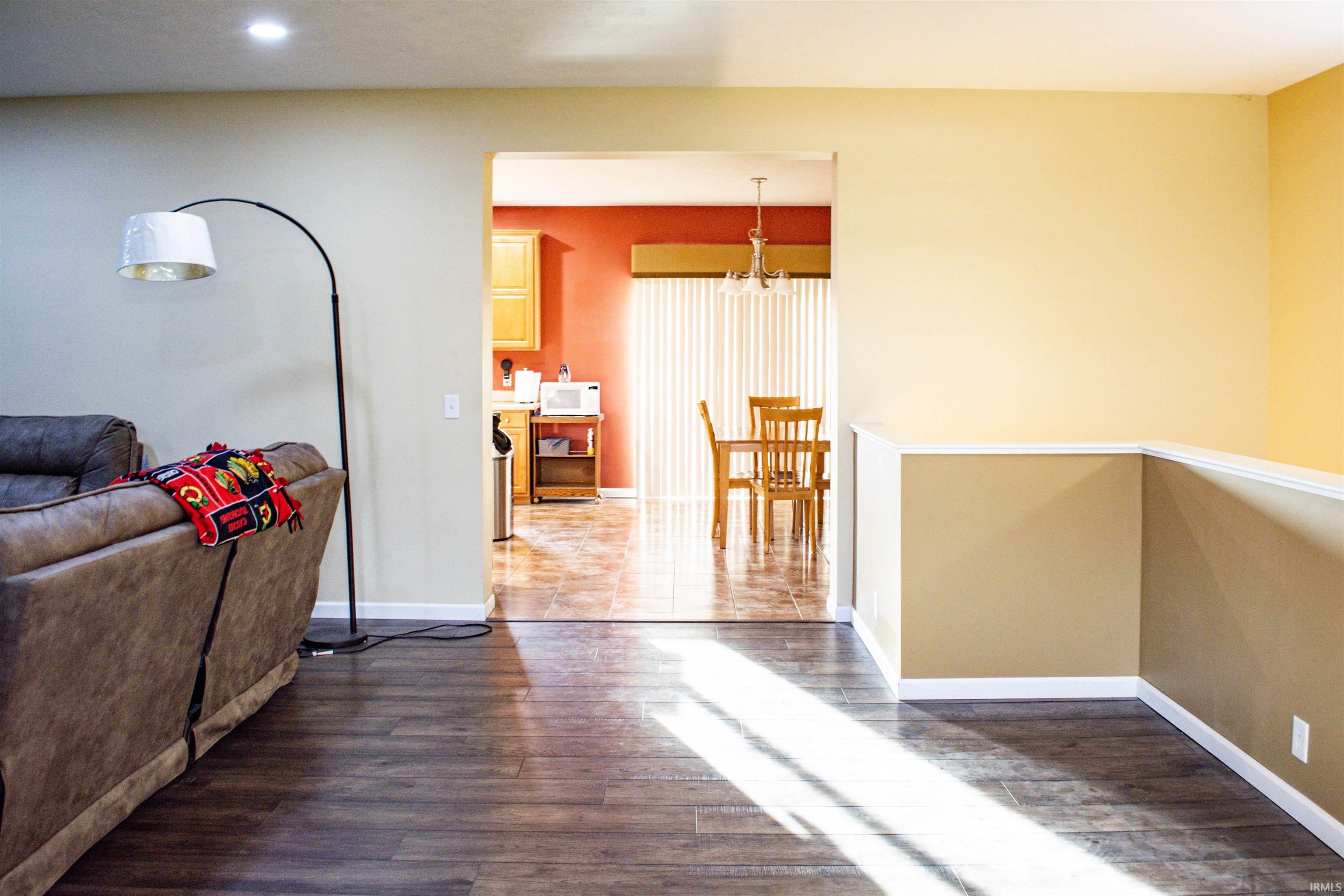 Corridor with dark wood-style floors and suspended lighting
