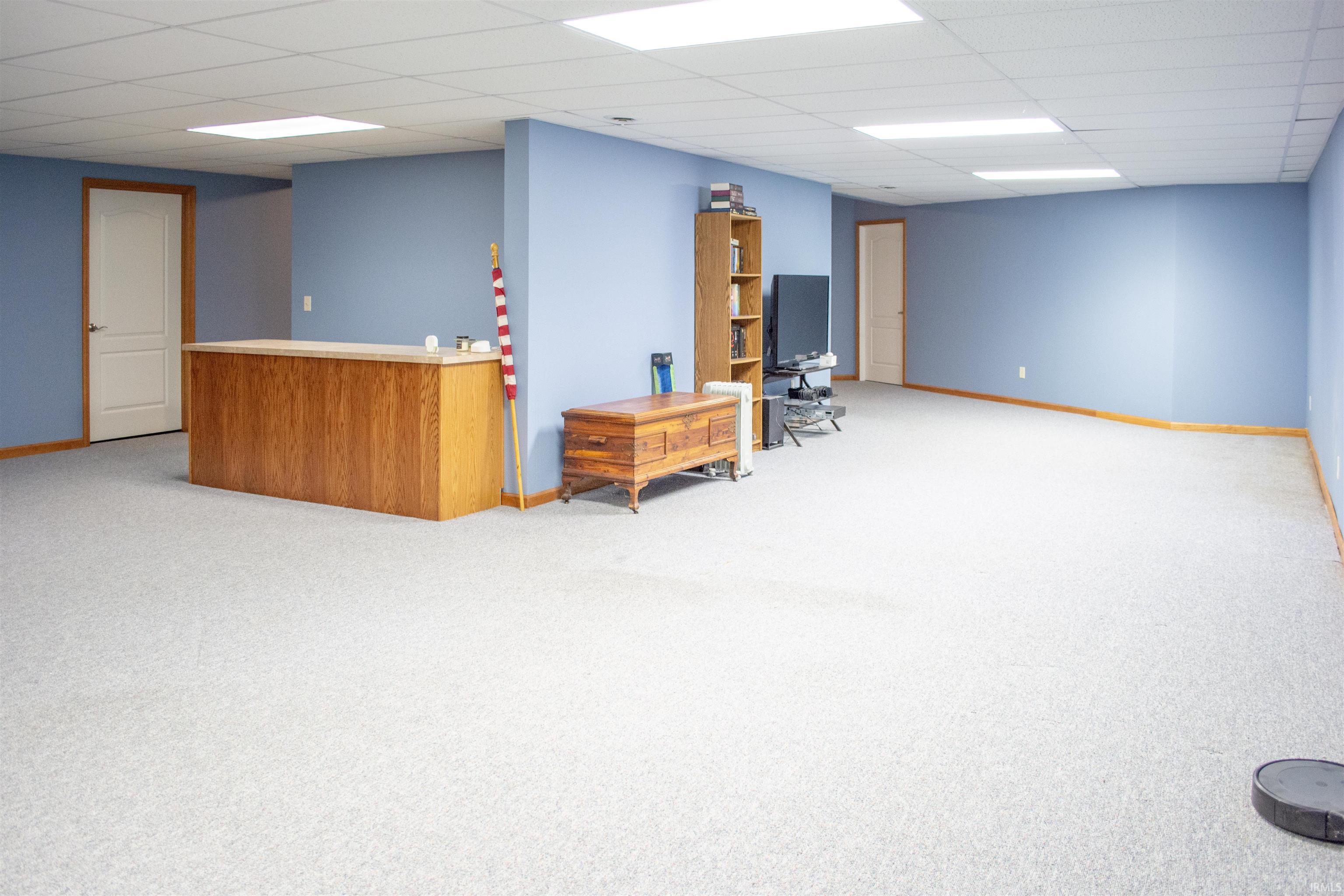 Finished basement with a paneled ceiling and light colored carpet
