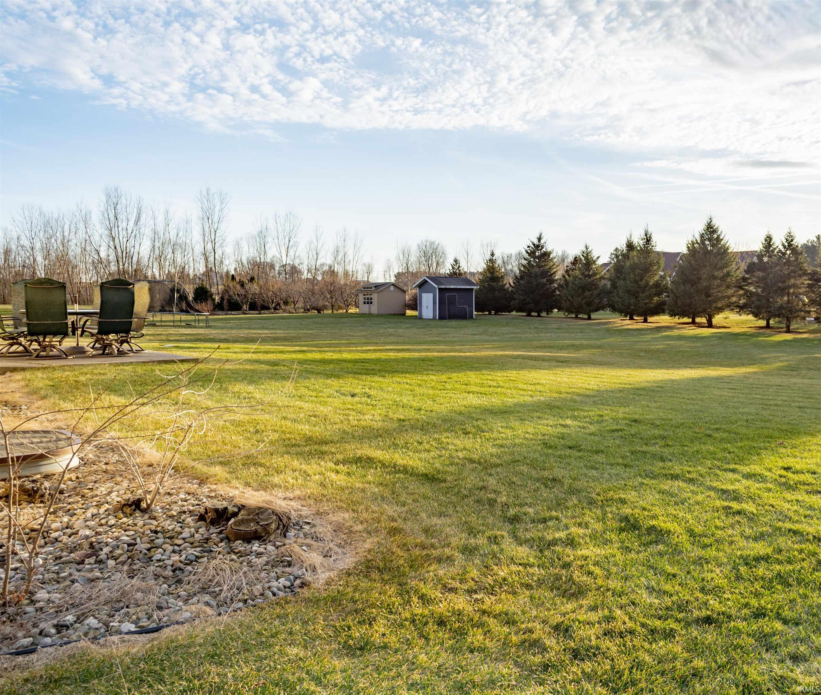 View of green lawn with a patio area and an outbuilding