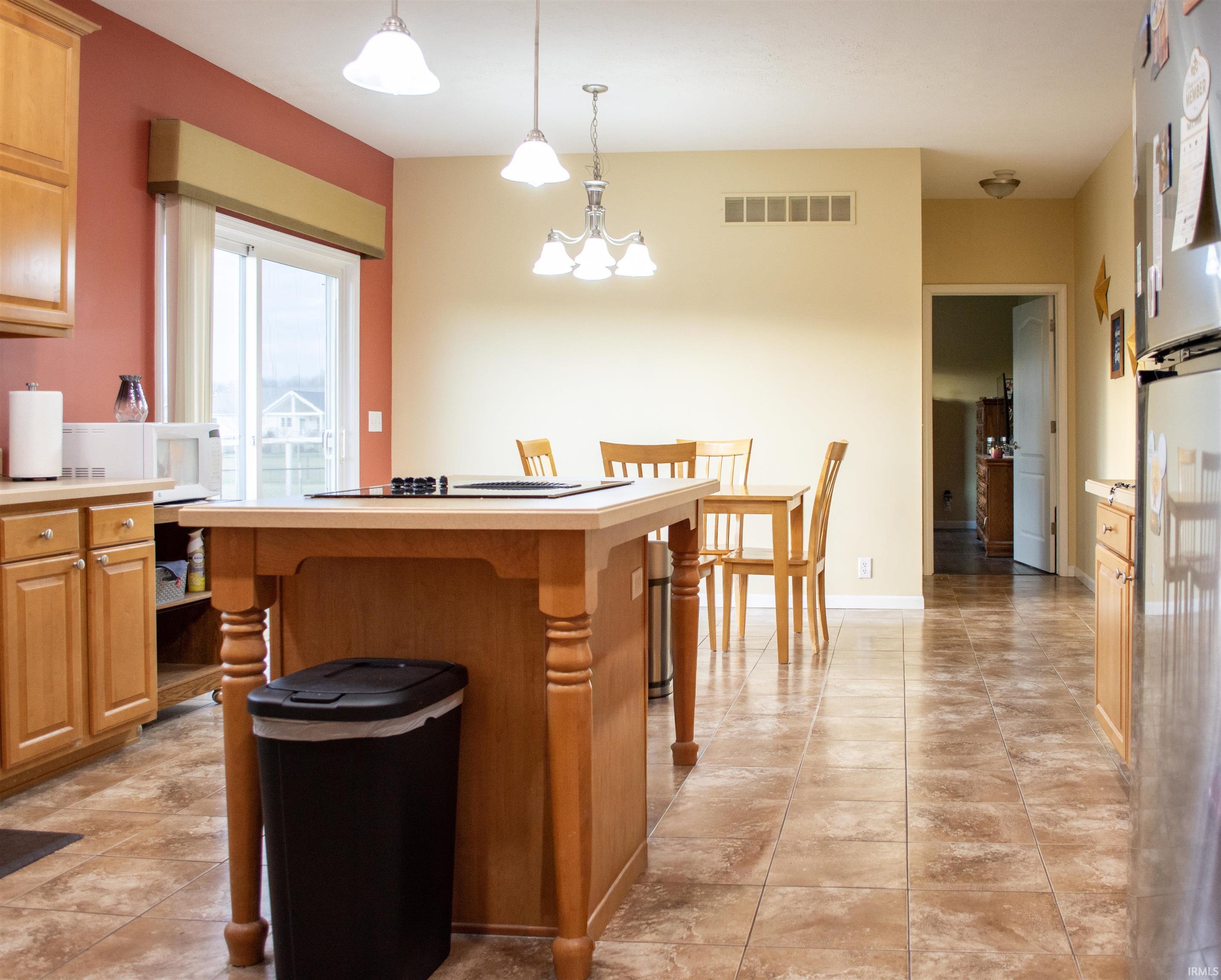 Kitchen with light countertops, a kitchen bar, hanging light fixtures, freestanding refrigerator, and a kitchen island