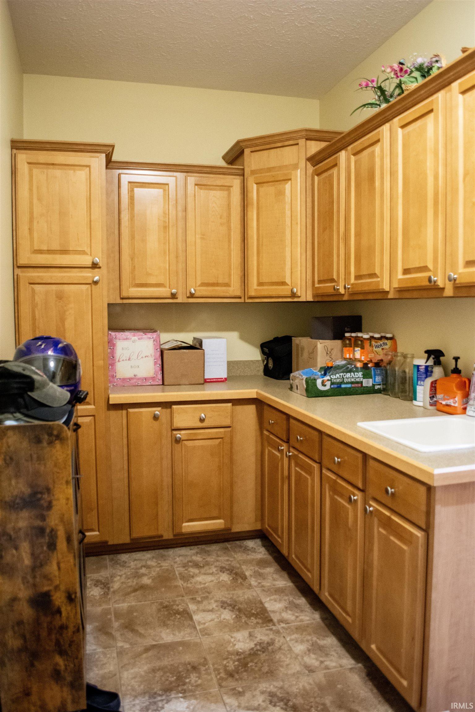 Kitchen featuring a textured ceiling, light countertops, and stone finish floors