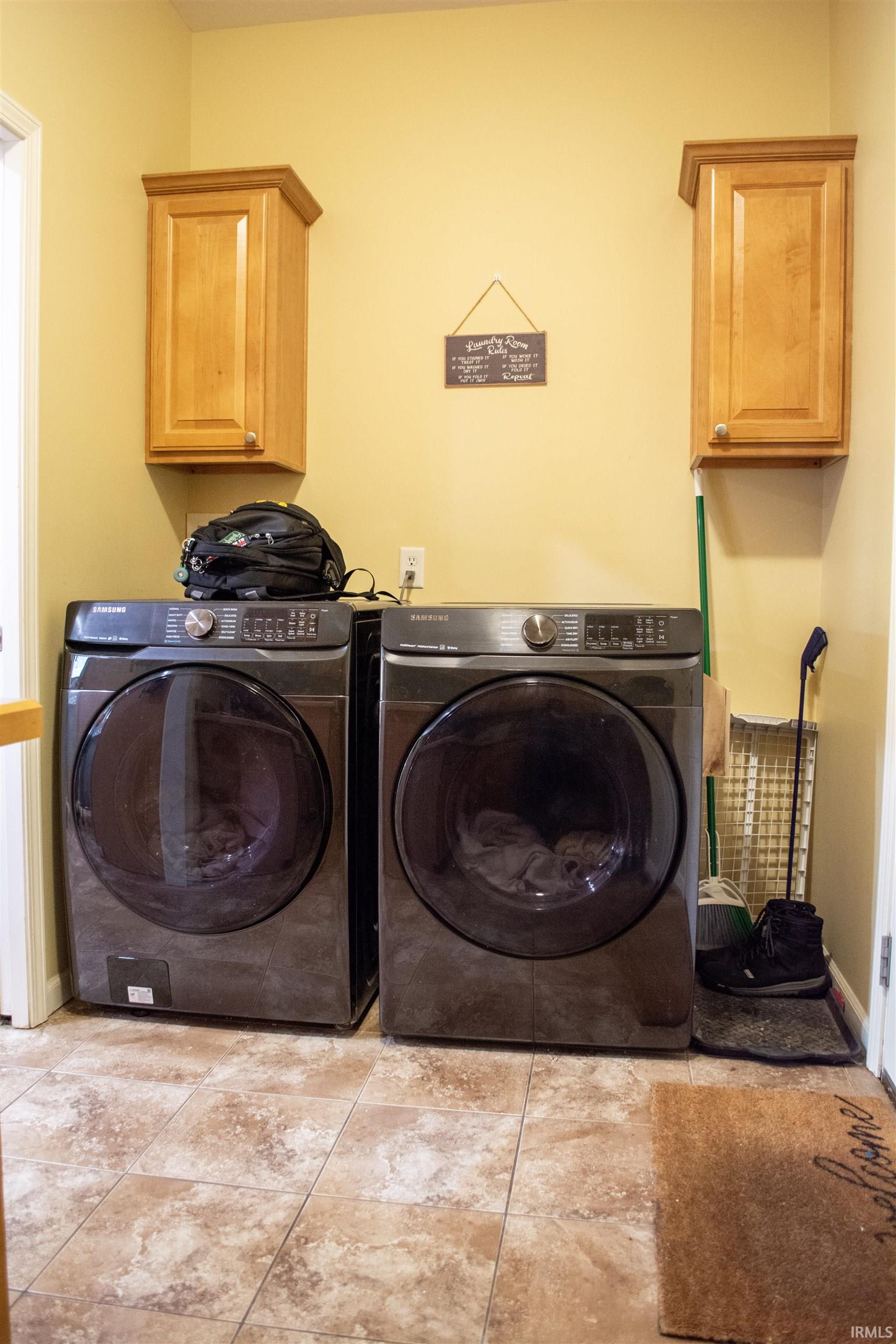 Laundry room with cabinet space, independent washer and dryer, and light tile patterned floors