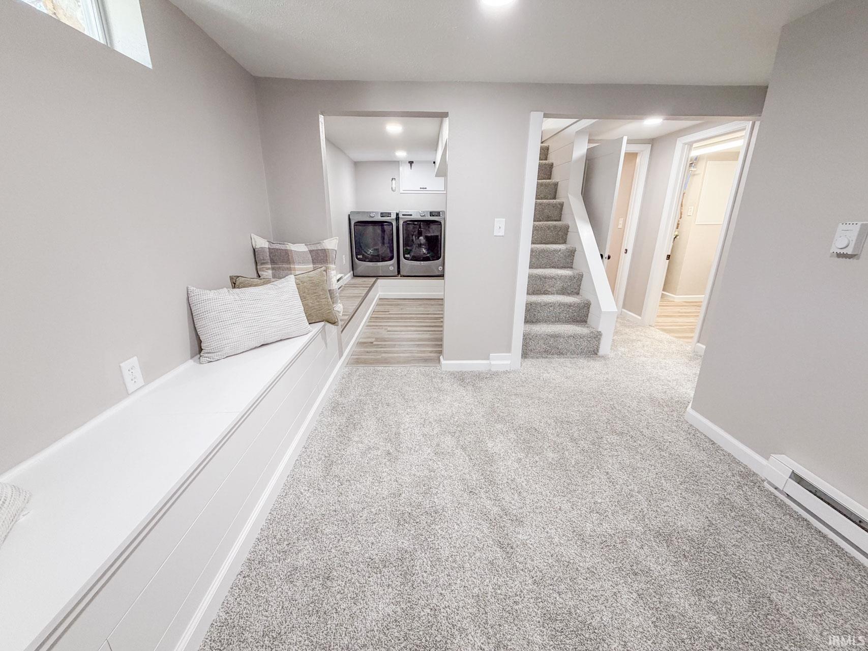 Living room with light carpet, washing machine and clothes dryer, baseboard heating, and recessed lighting