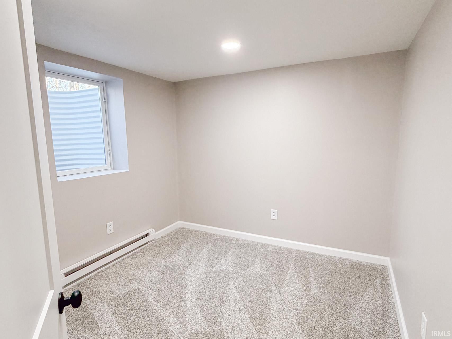 Unfurnished room with a baseboard radiator and light colored carpet