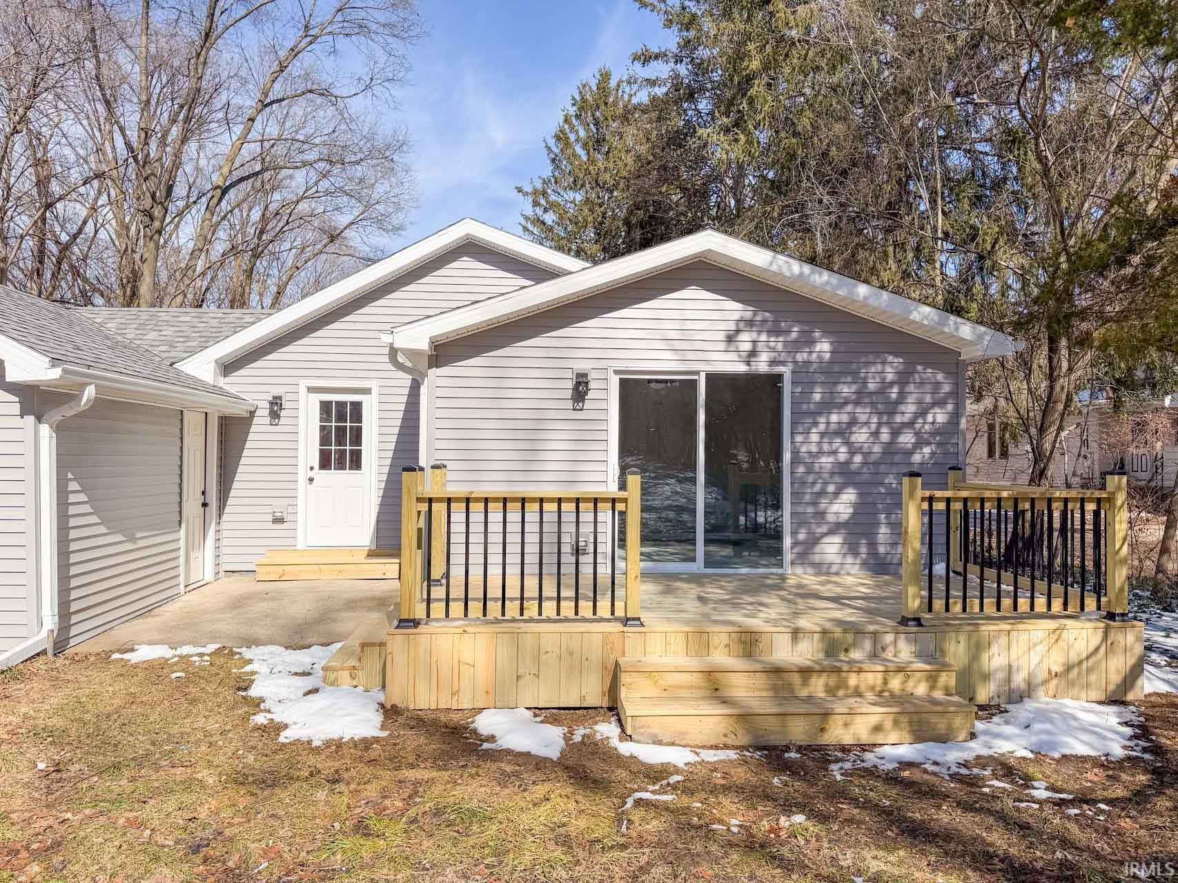 Snow covered rear of property with a deck