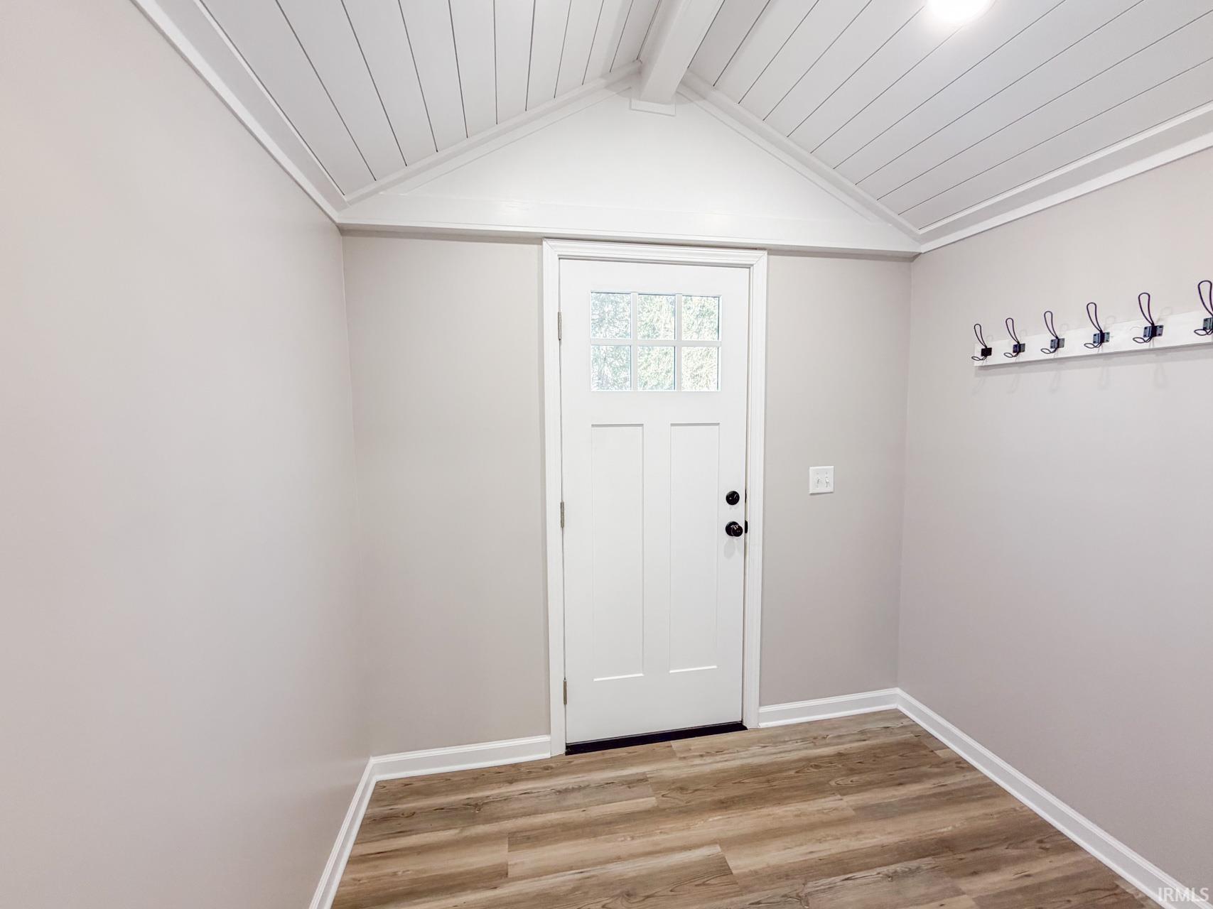 Doorway with wood finished floors and a wood ceiling with exposed beams