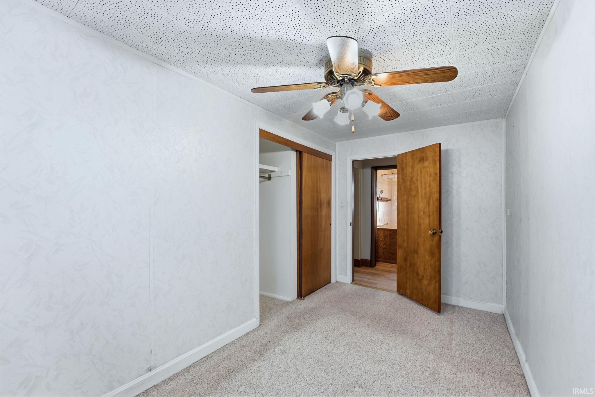 Unfurnished bedroom with light colored carpet, ceiling fan, and a closet