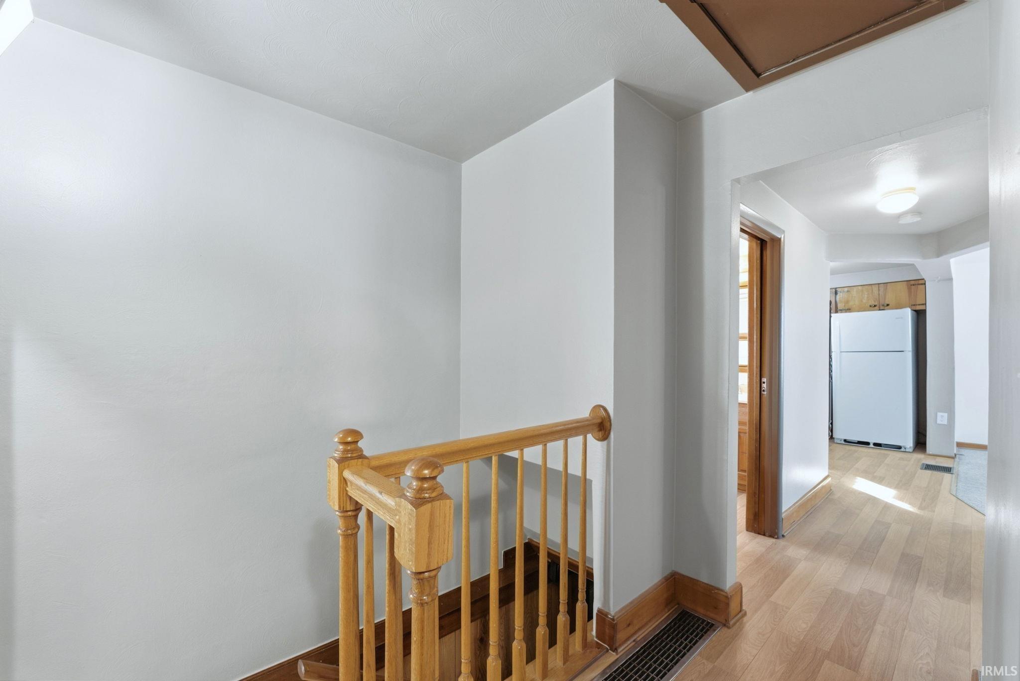 Hall with an upstairs landing and light wood-type flooring