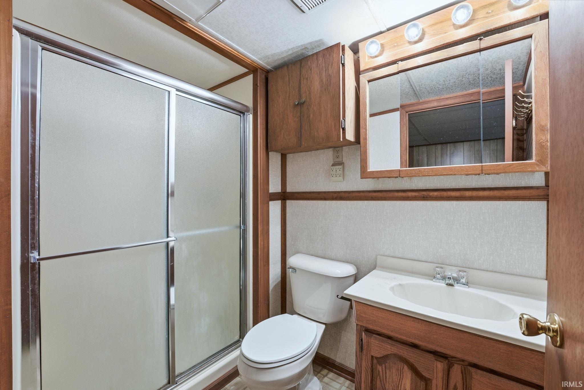 Bathroom featuring vanity, a shower stall, and wallpapered walls