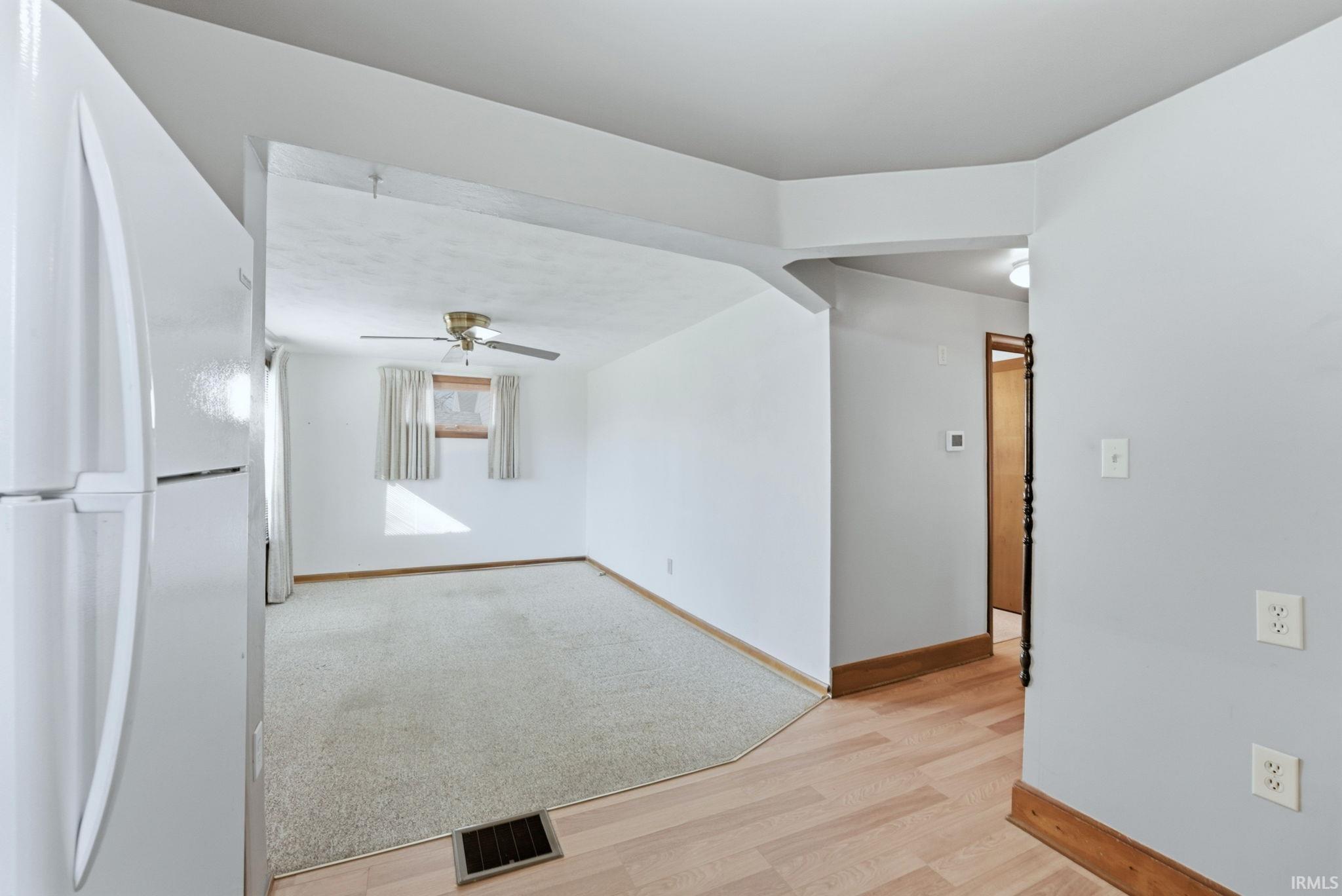 Empty room with light wood-style flooring, a barn door, and a ceiling fan