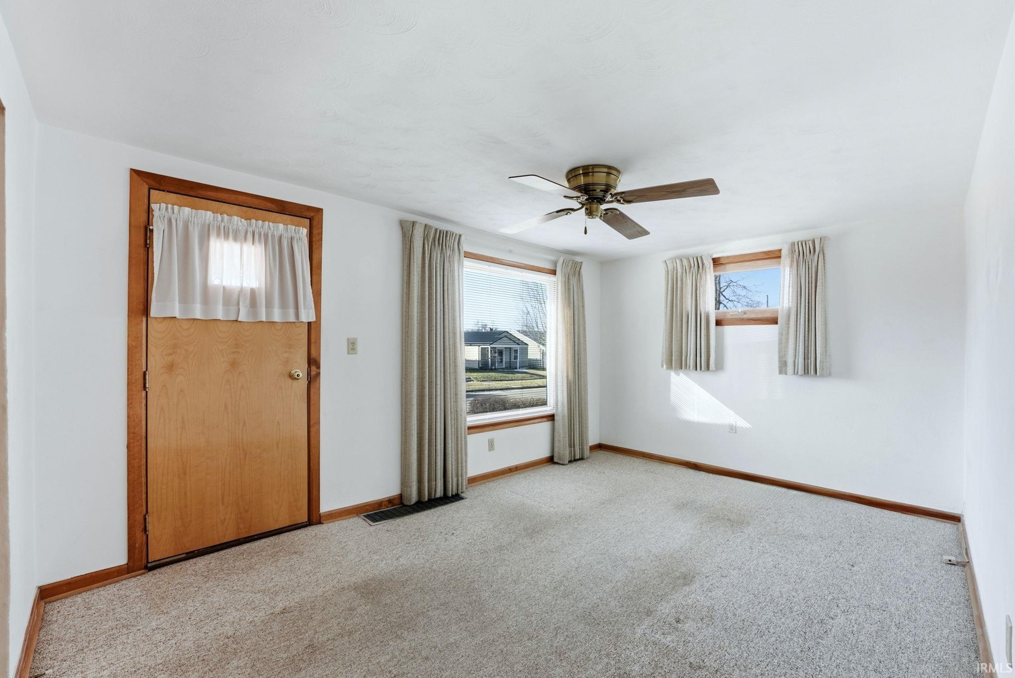 Unfurnished room with light colored carpet and ceiling fan