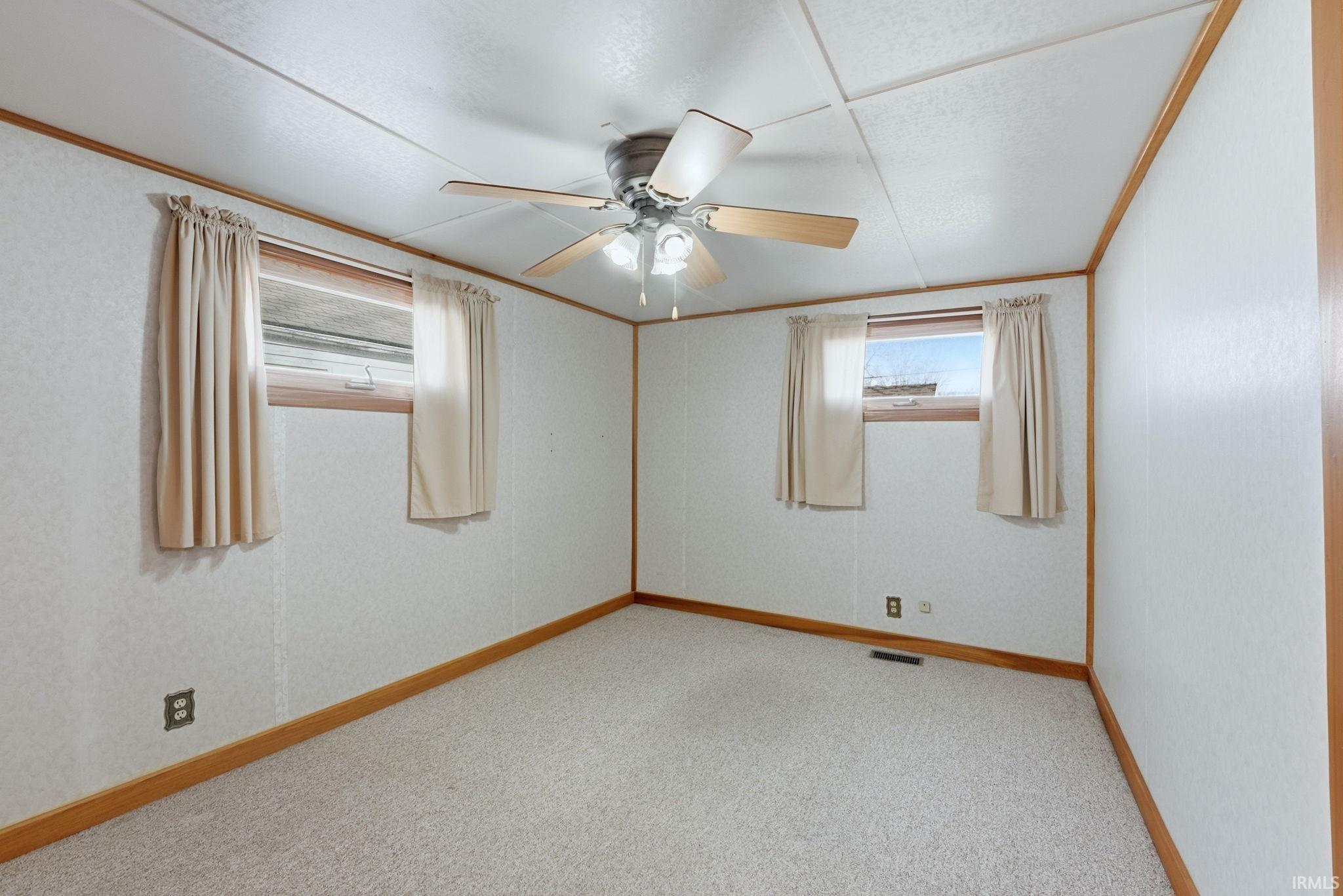 Empty room featuring light colored carpet, a ceiling fan, and crown molding