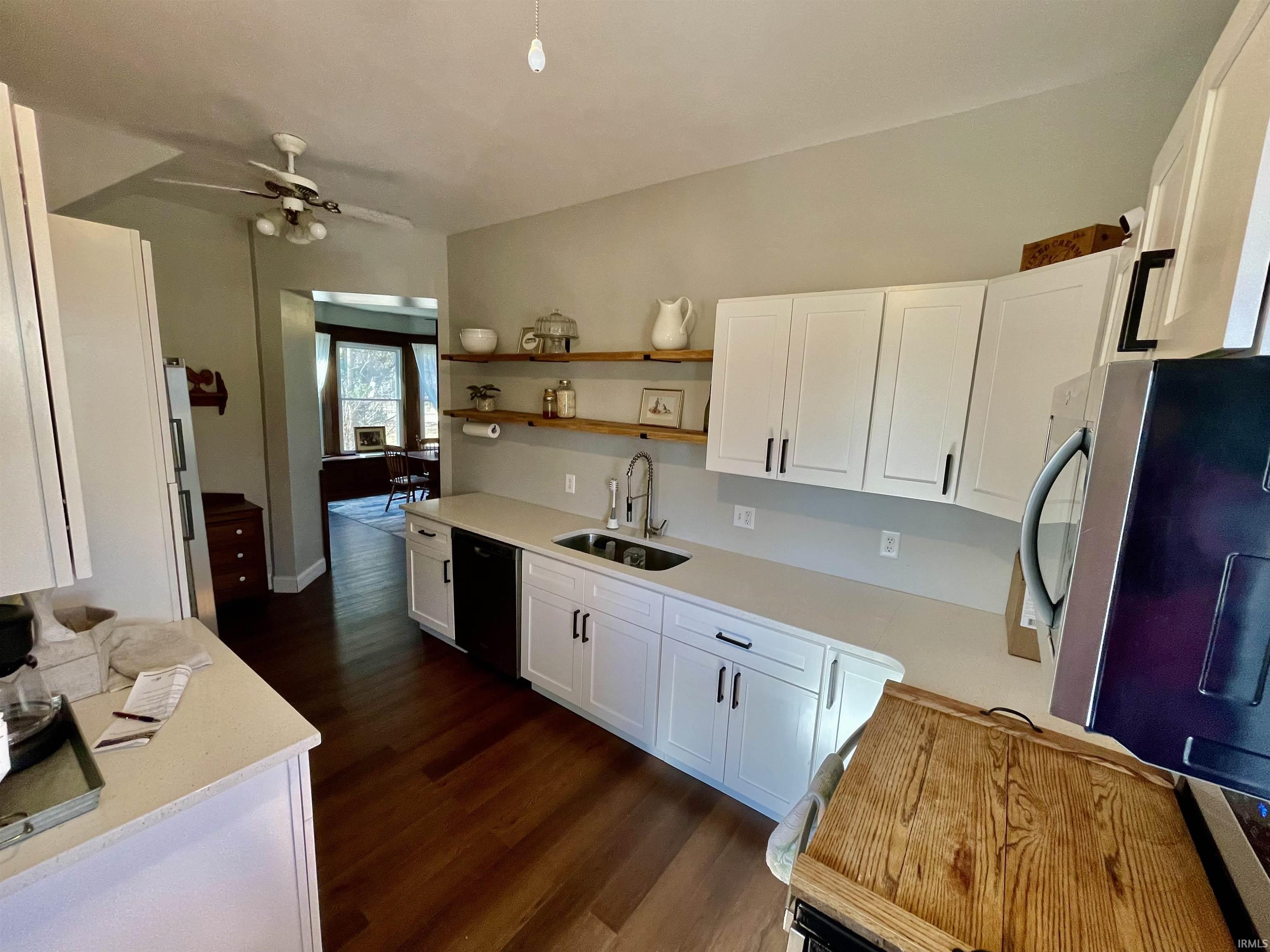 Entrance into kitchen with white cabinetry, open shelves, new flooring.