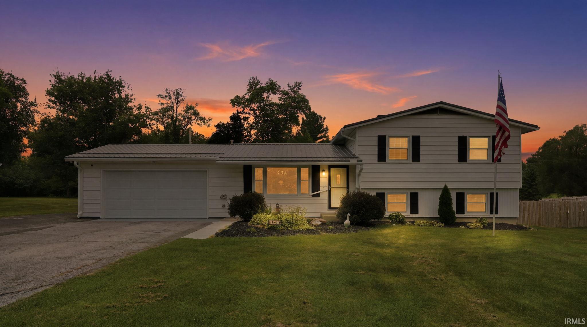 Split-level residence featuring white siding and a metal roof
