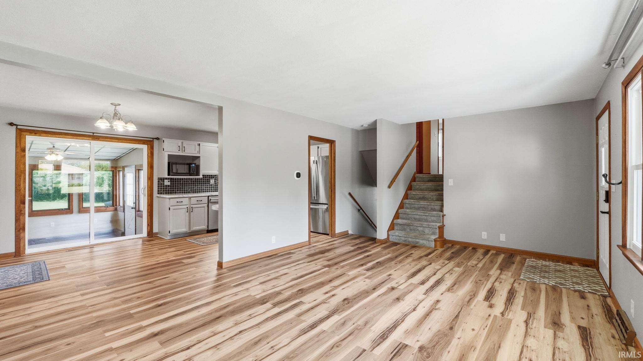 Open concept living space featuring wood-finish flooring, light gray walls, and natural wood trim