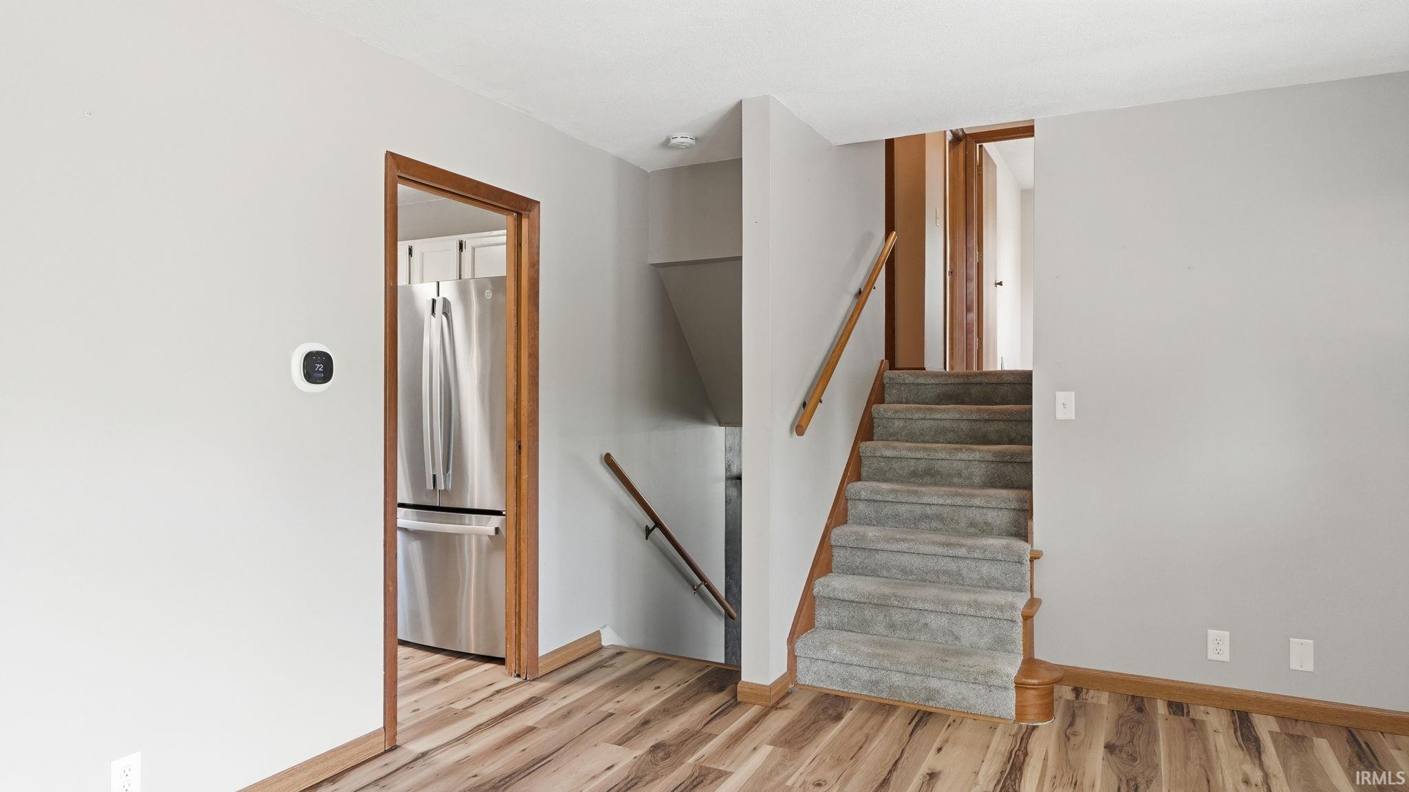 Interior staircase with carpeted treads and wood-finish risers, featuring a wood handrail
