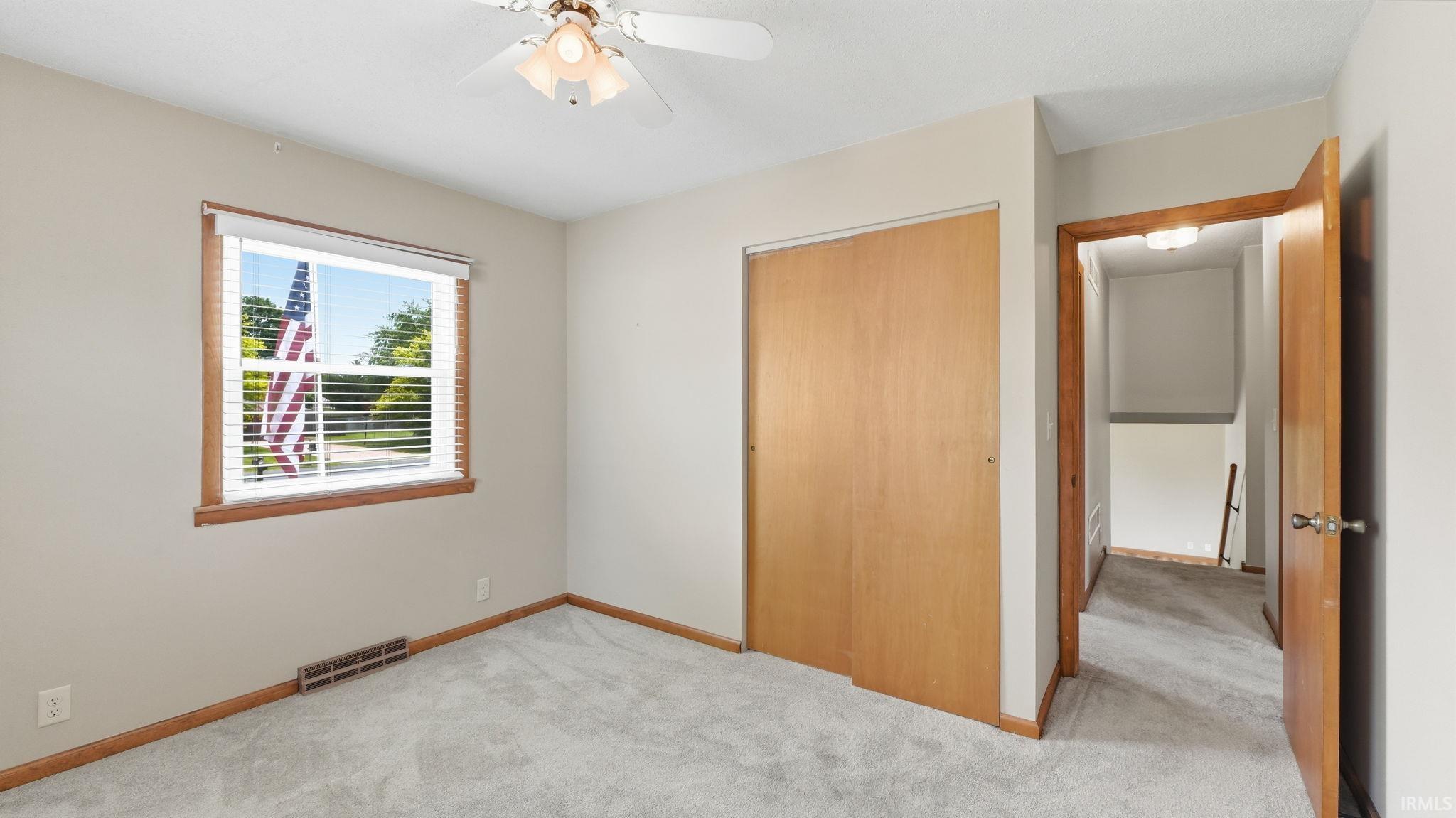 Bedroom featuring light neutral wall paint, light gray carpet, and wood trim