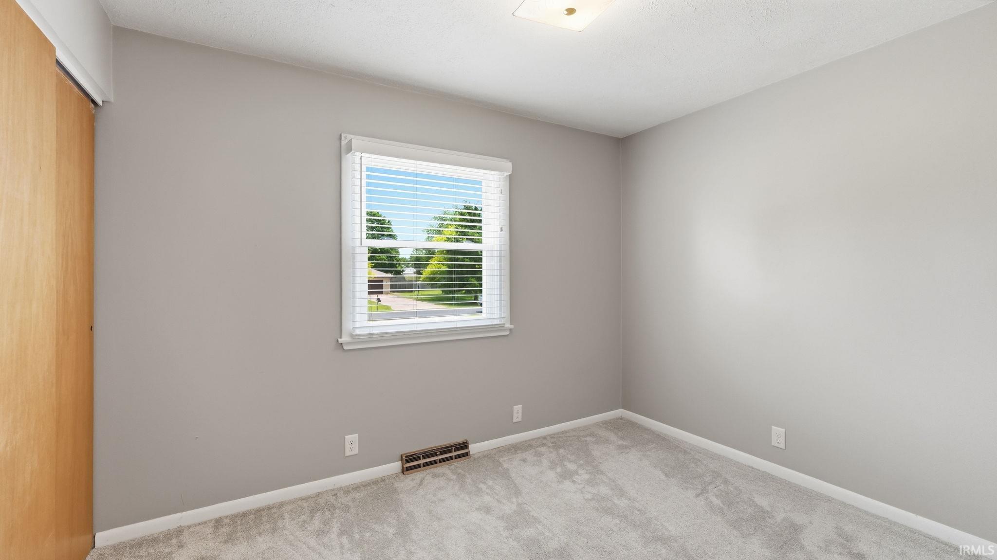 Bedroom featuring neutral gray walls, light gray carpet, and a window with white blinds